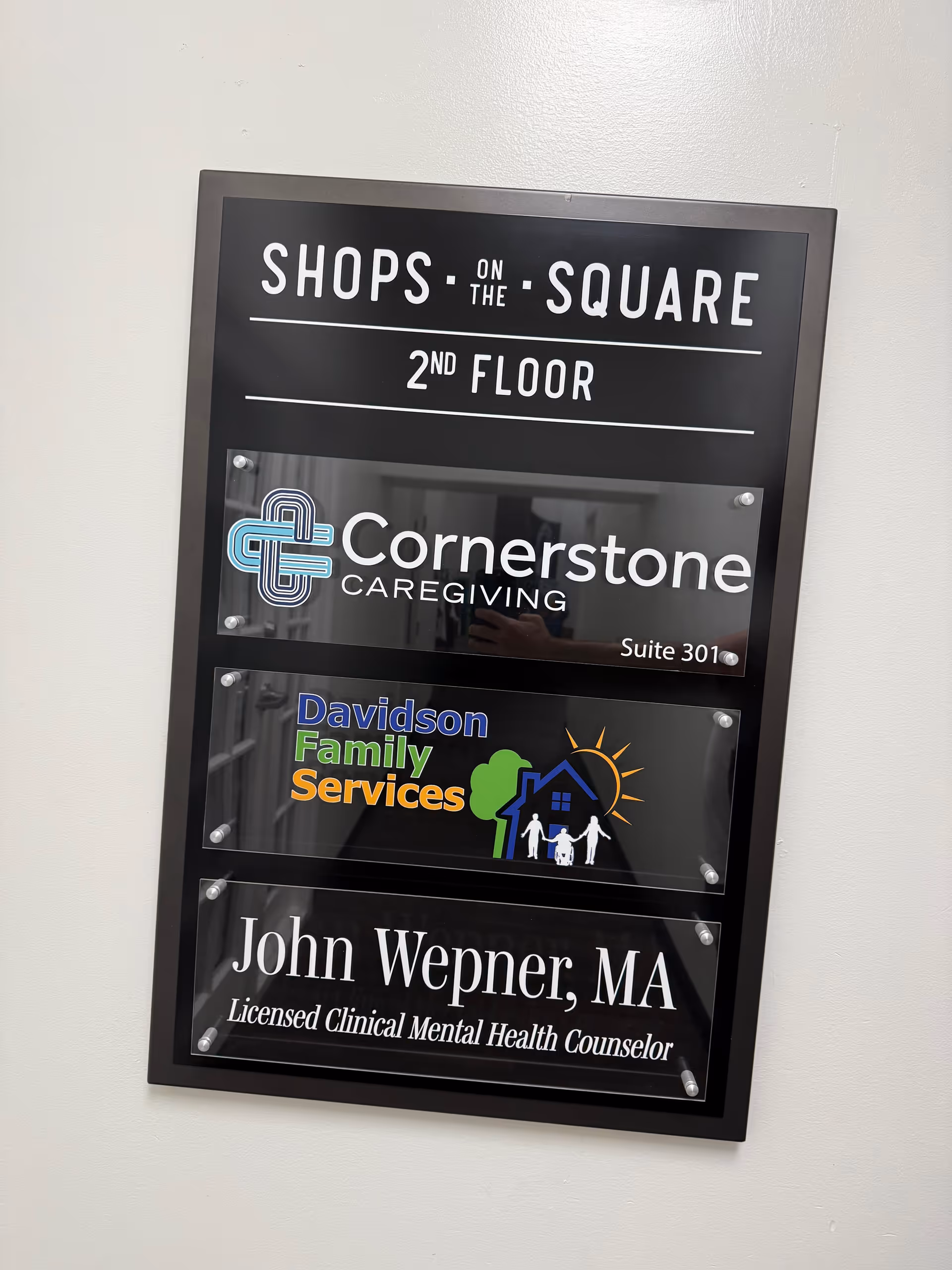 Interior wall plaque displaying Cornerstone Caregiving, Davidson Family Services, and a counseling sign.