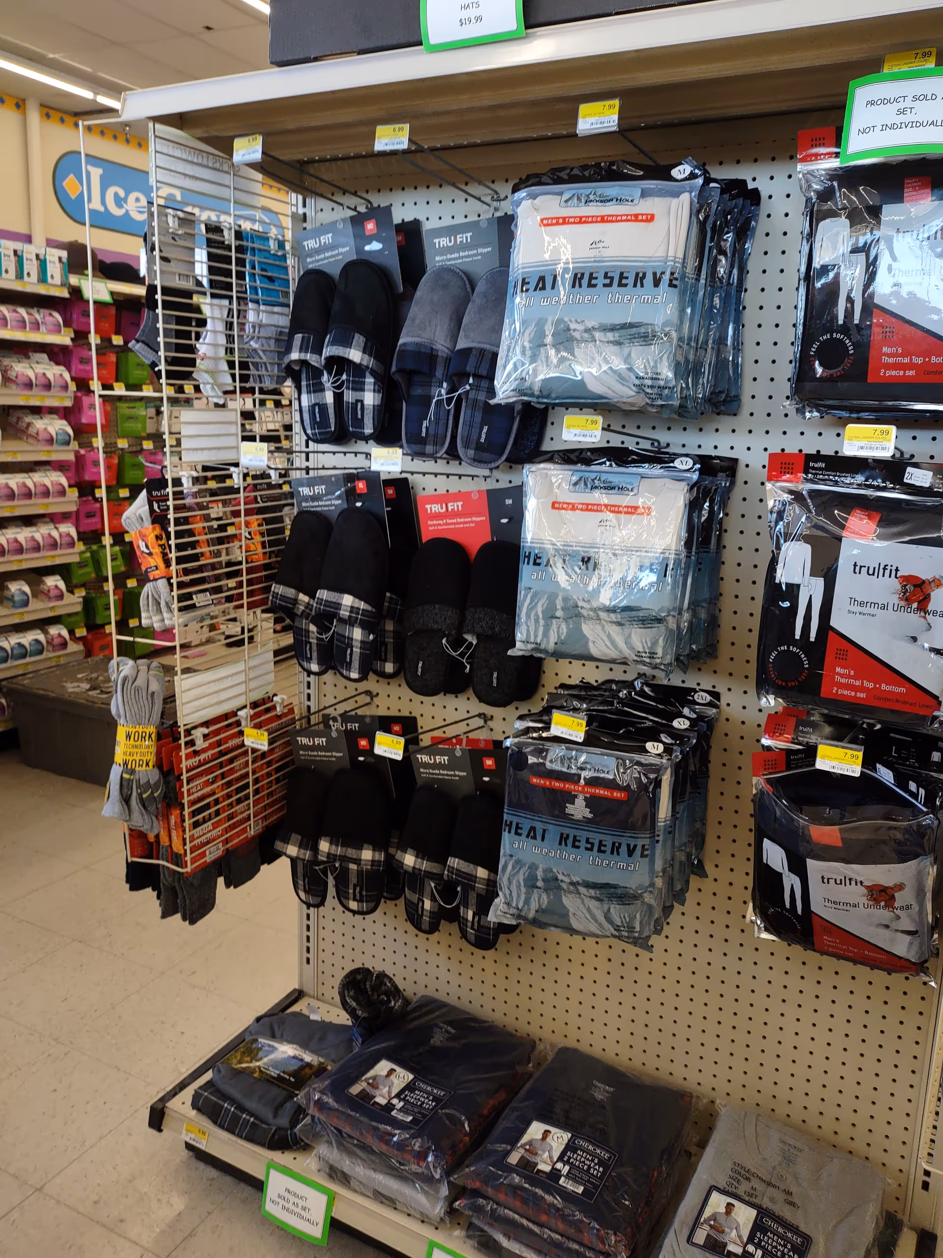 Store aisle with packaged slippers, socks, and warm apparel on pegboard shelves.