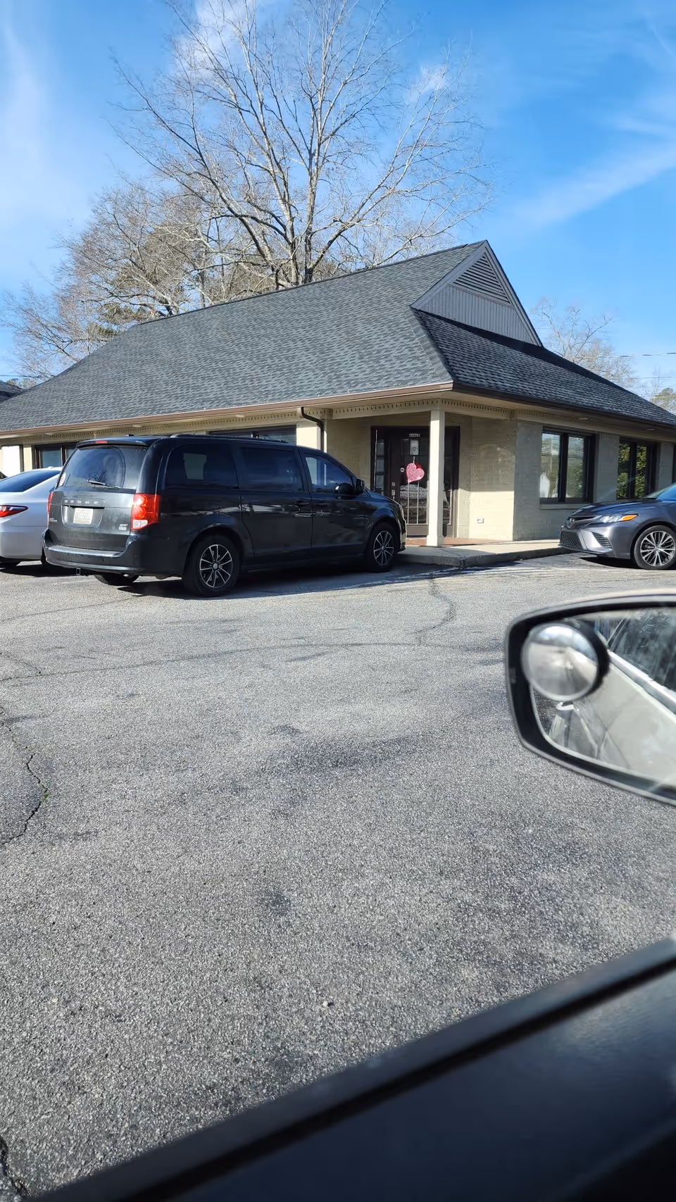 Exterior view of a single-story facility with parked cars in front.