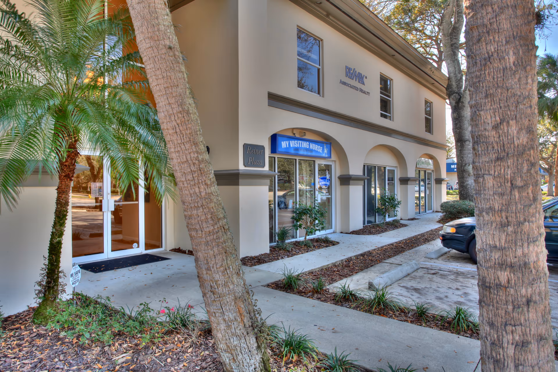Exterior view of a two-story building with 'My Visiting Nurse' storefront and palm trees.