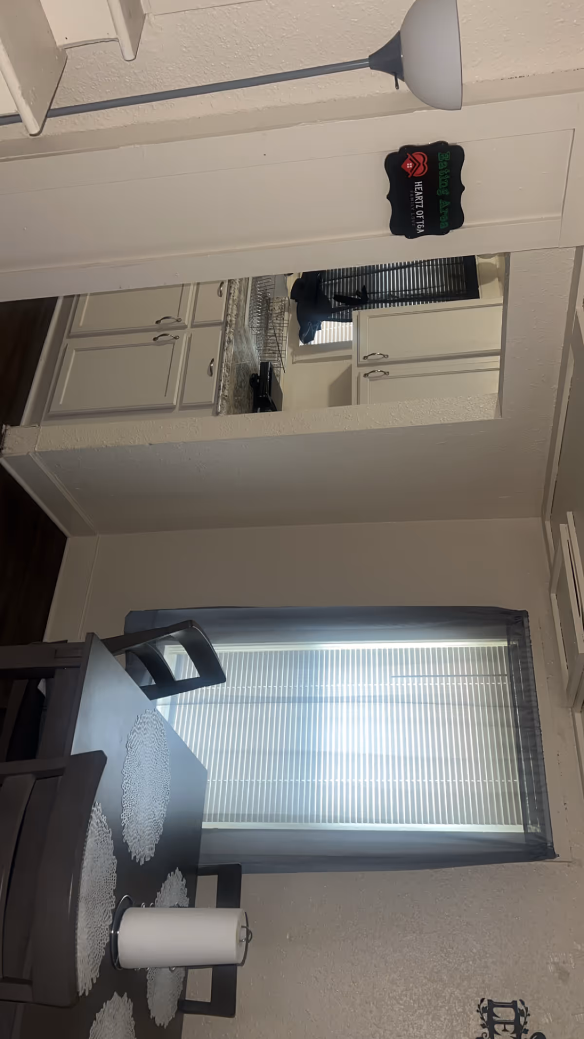 Compact dining area with table, chairs, cabinets, and a window with blinds.