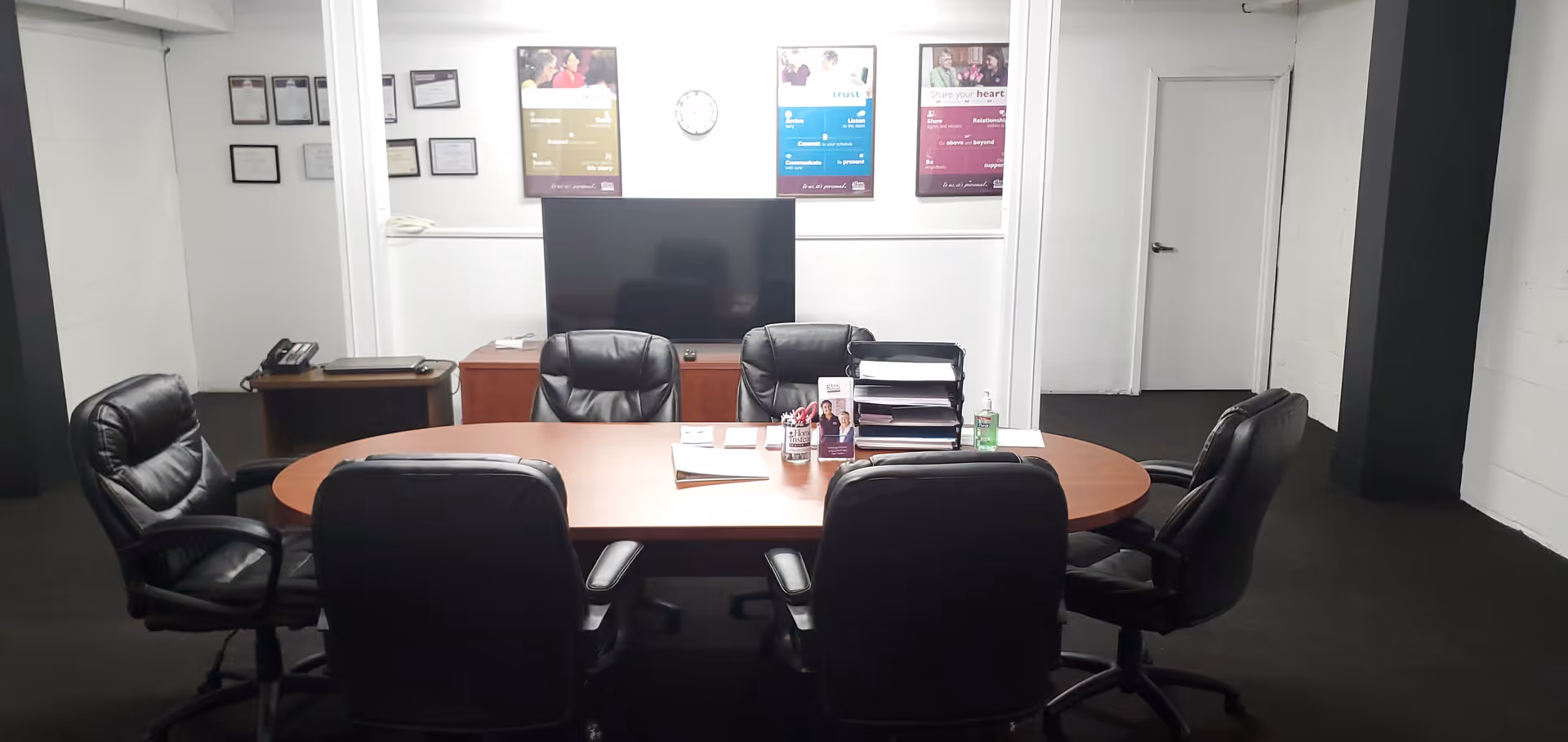 Round conference table with black leather chairs in a formal meeting room.