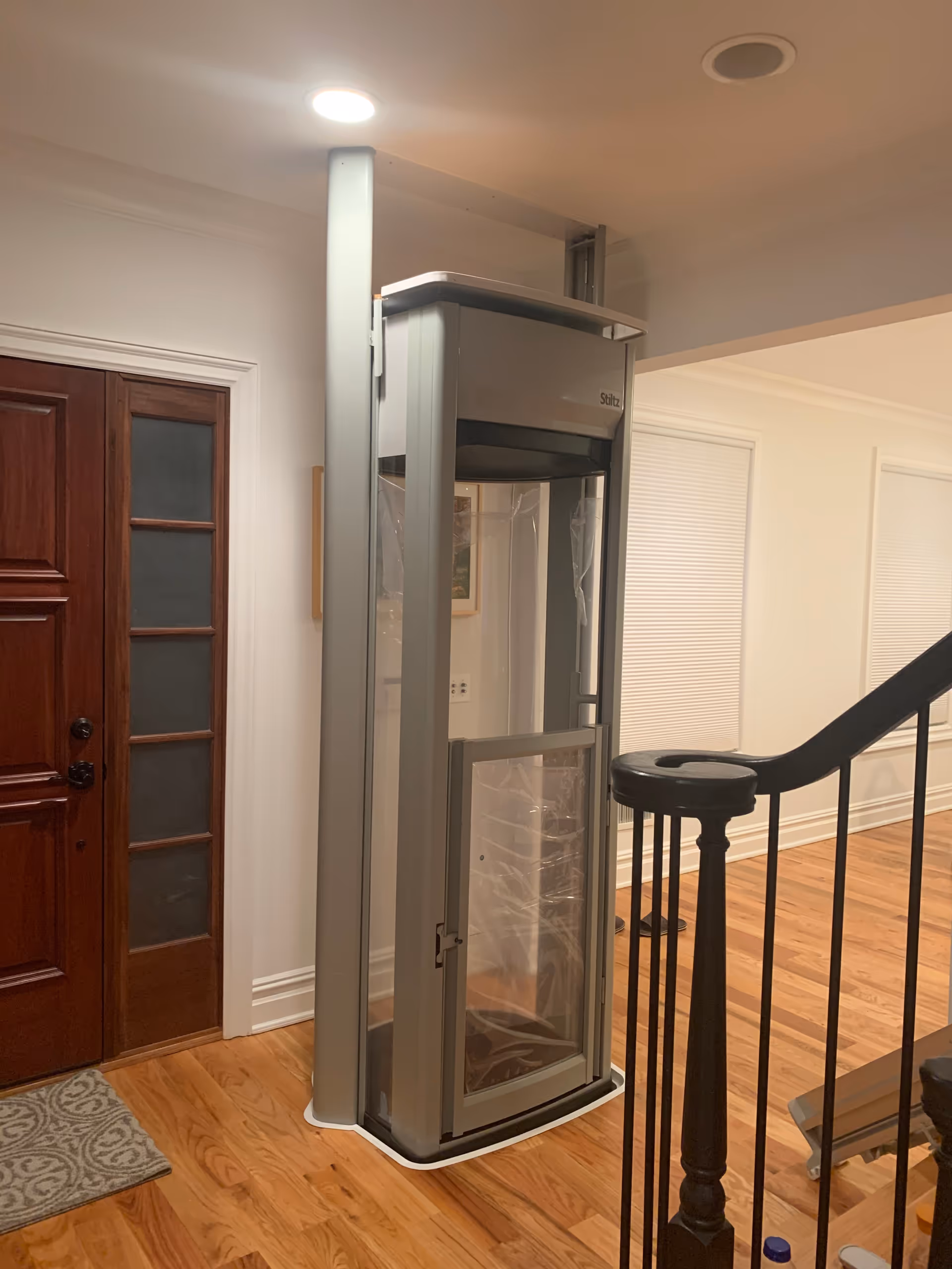 Indoor hallway featuring a vertical residential elevator lift beside a wooden door.