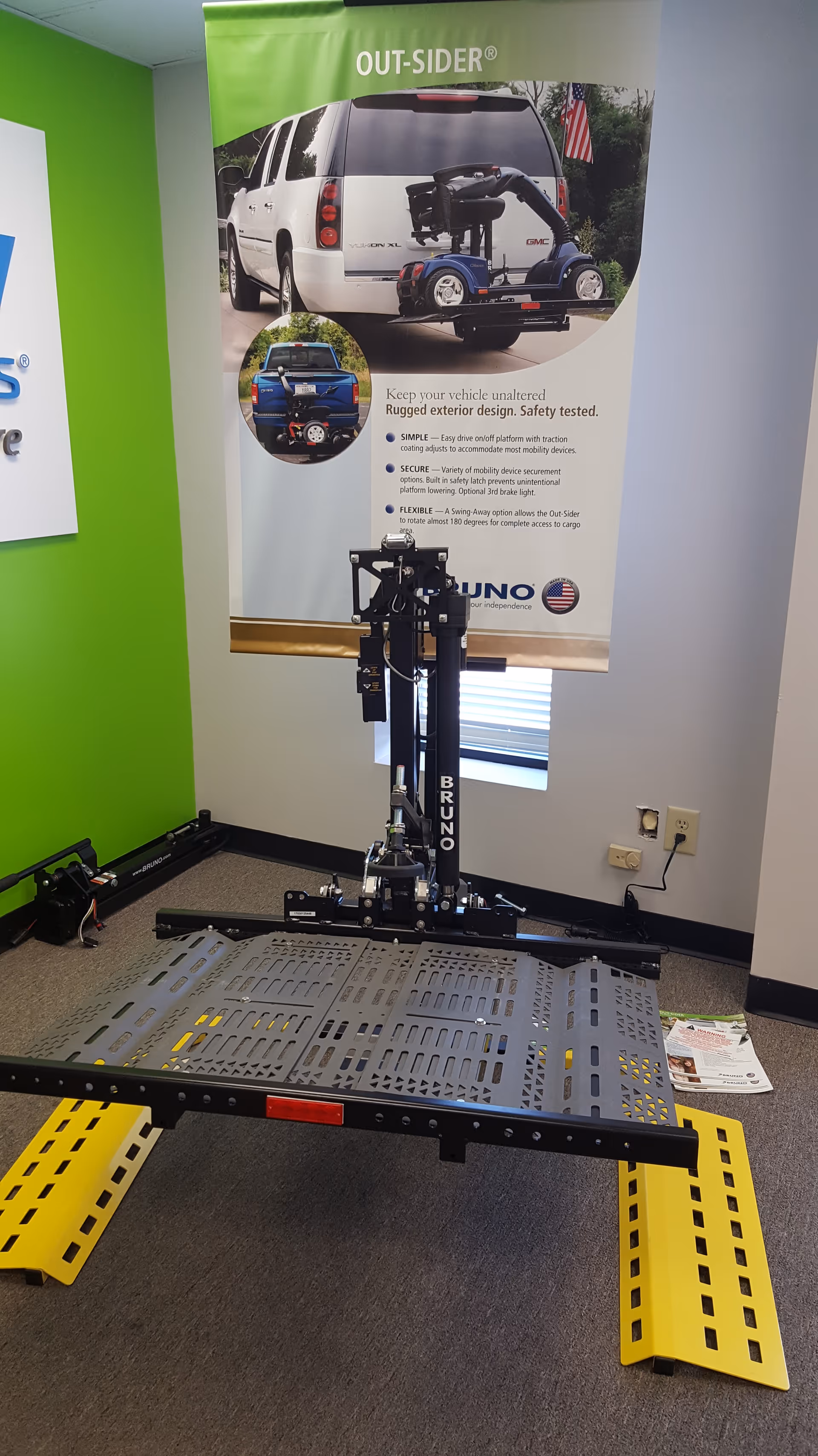 Indoor showroom with a wheelchair lift platform and promotional mobility equipment banner.