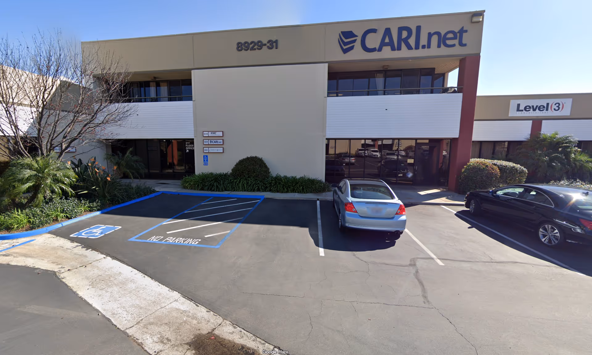 Exterior view of a two-story commercial building with handicap parking and parked cars.