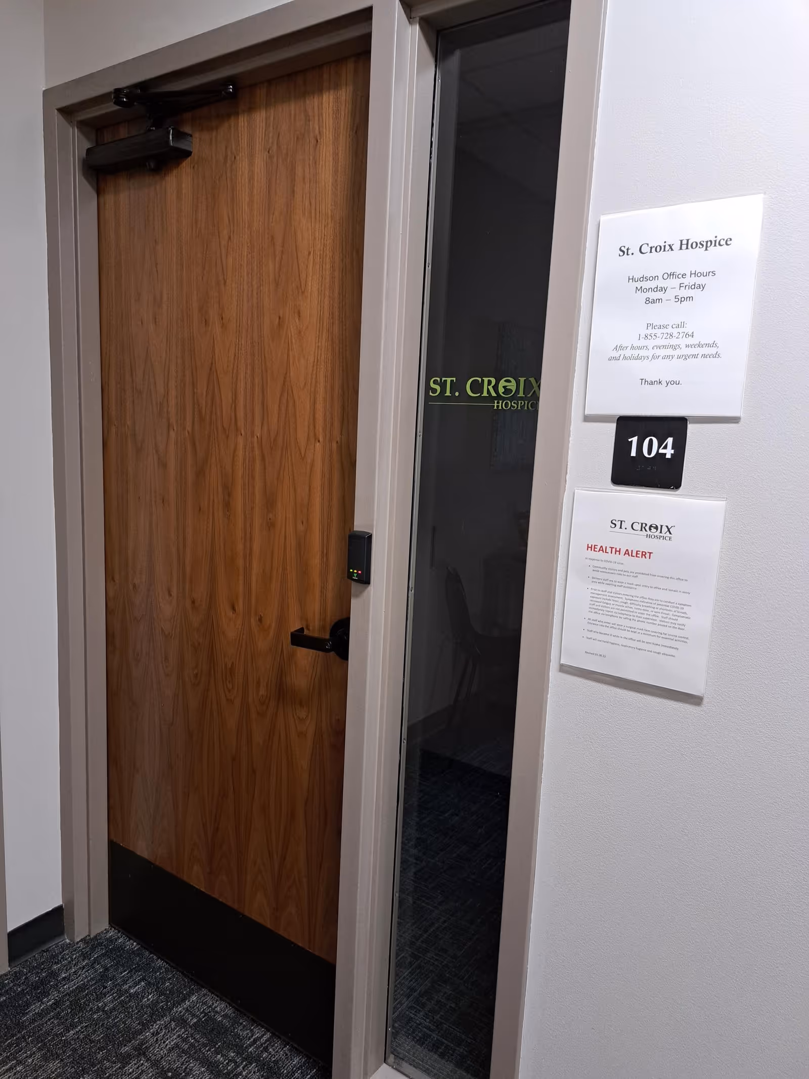 Interior hallway with a wooden door, room number 104, and St. Croix Hospice signage.