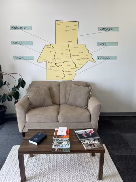 A beige couch and coffee table in a lounge with a large wall map mural.