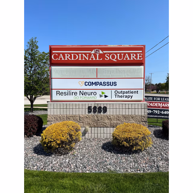 Outdoor sign at Cardinal Square displaying Compassus branding and healthcare tenants.