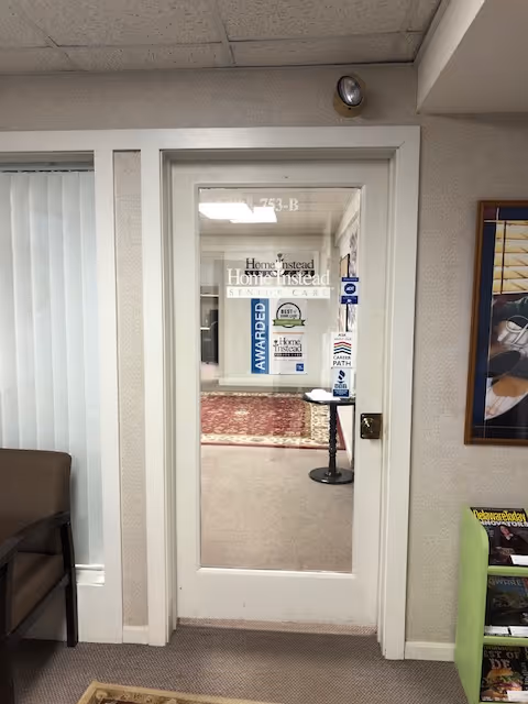 Doorway to a Home Instead interior lobby with signage, carpet, and waiting area visible.