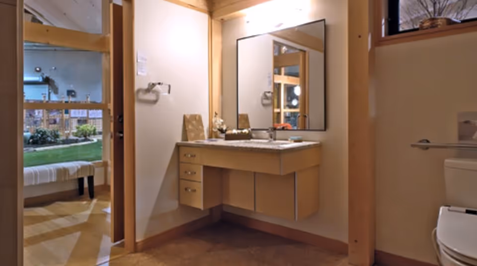 Bathroom vanity with sink, mirror, and adjacent toilet amid wood trim.