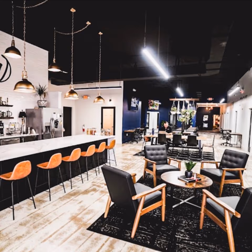 Modern senior living lounge with a long bar, orange stools, and seating area.