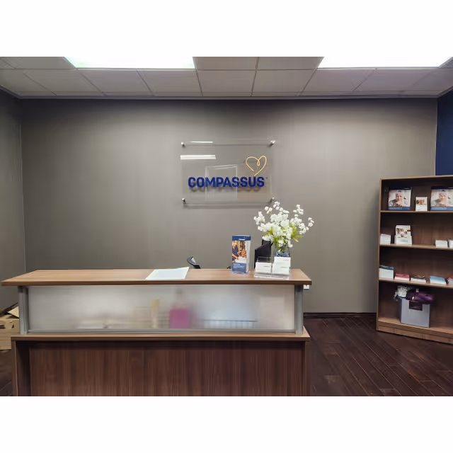Reception desk in a Compassus lobby with flowers and a magazine shelf.