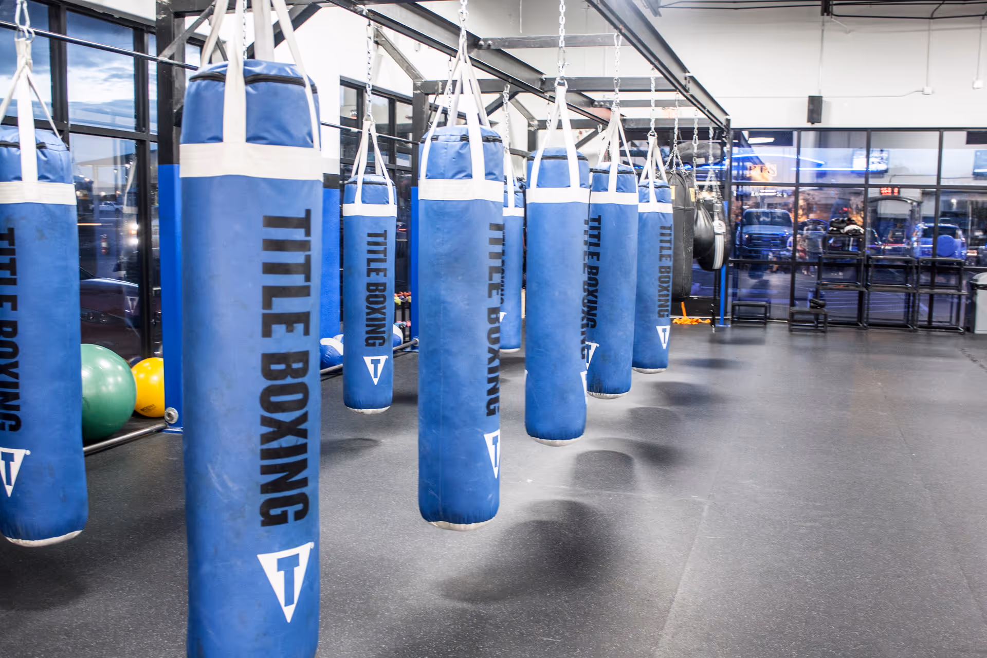 Blue punching bags hang from ceiling in a spacious gym area.