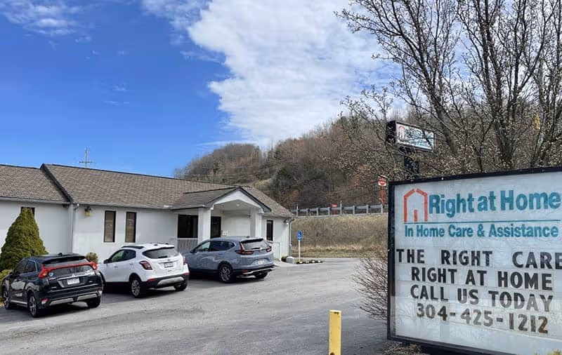 Exterior view of Right at Home facility with parked cars and a large sign.