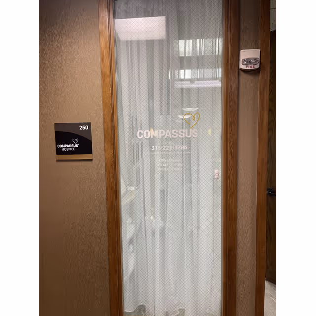 Glass door with Compassus sign in a hallway; interior office entries visible