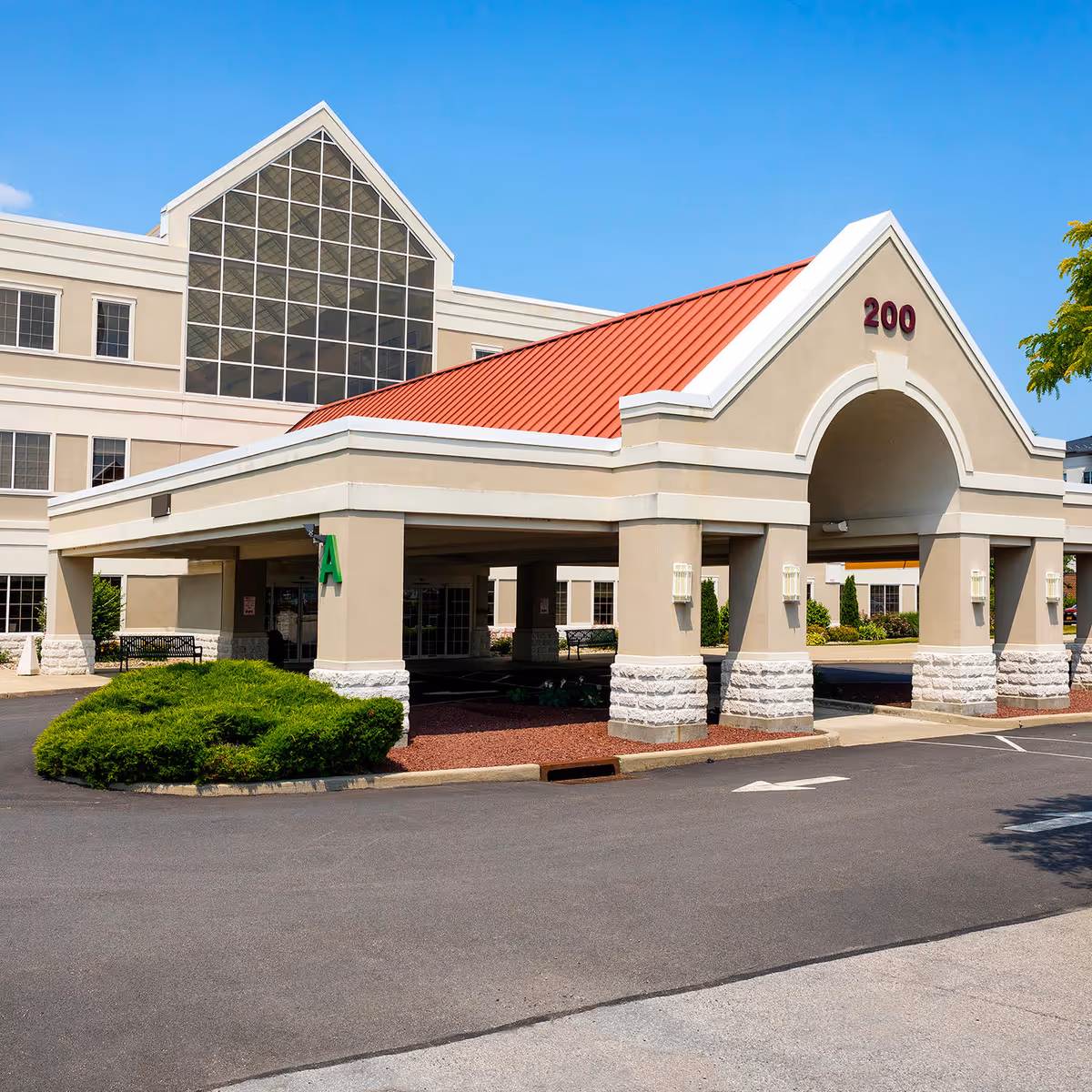 Exterior view of a senior living facility entrance with a red roof and 200 sign.