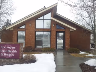 Brick-faced senior care building with large windows, glass entrance, and snowy walkway.