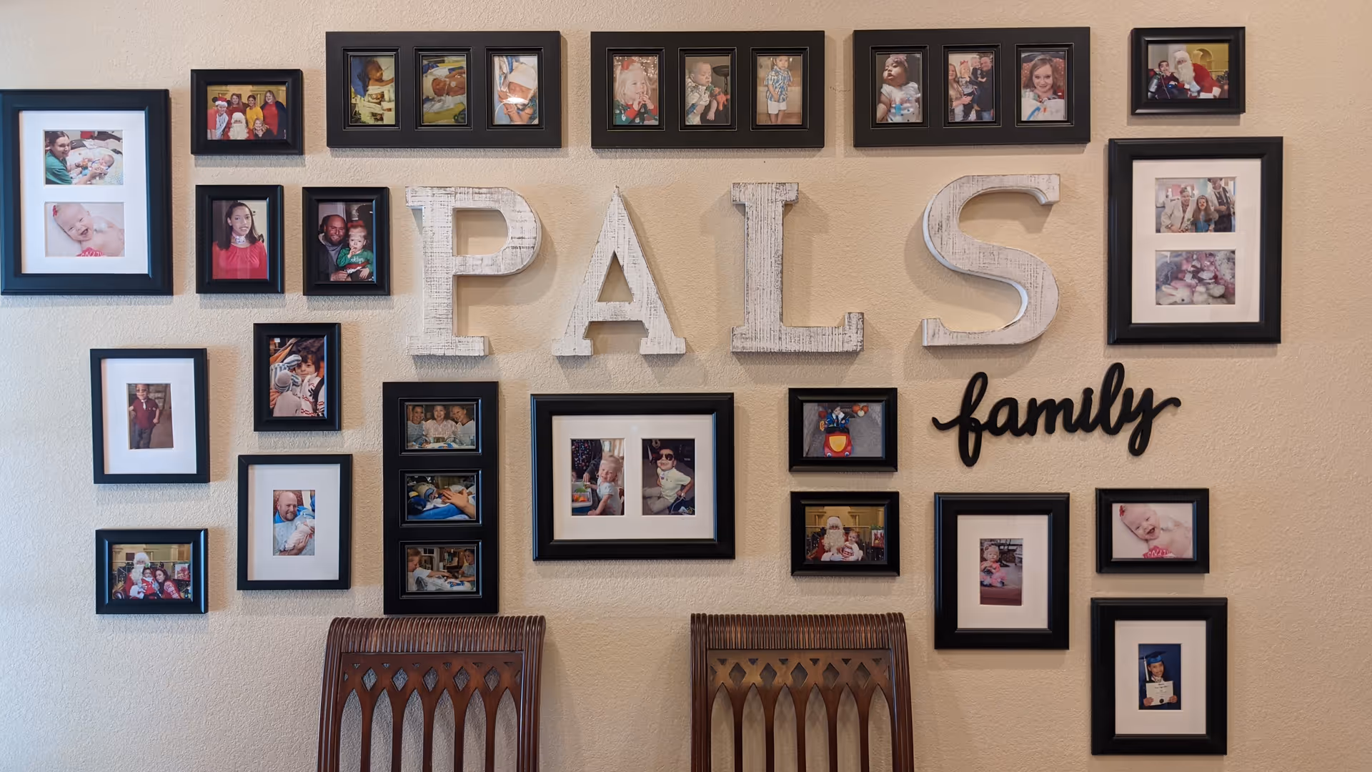Interior wall with framed family photos and large PALS lettering in a common area.
