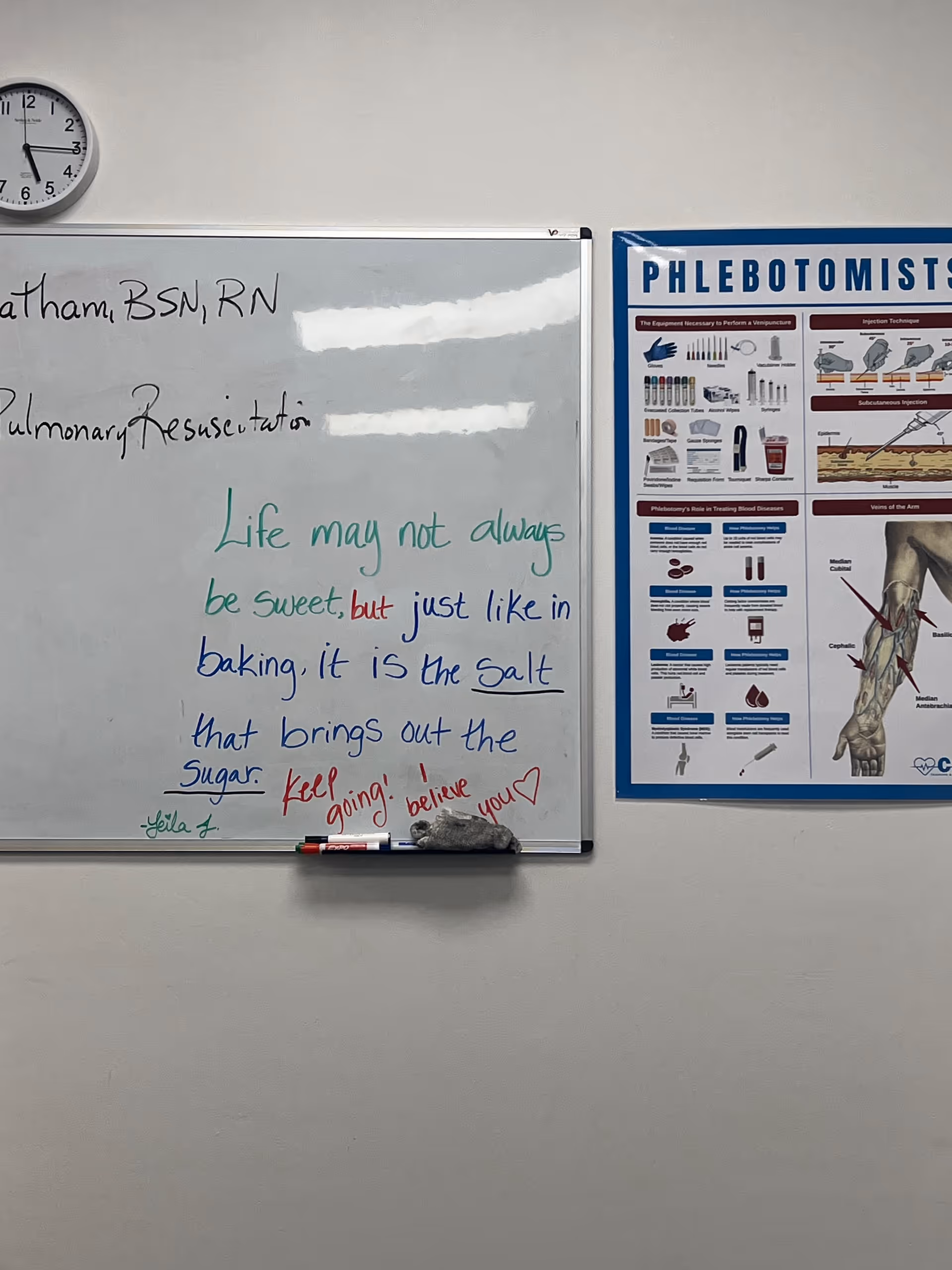 Whiteboard with handwritten motivational quote beside a phlebotomy poster in a classroom.