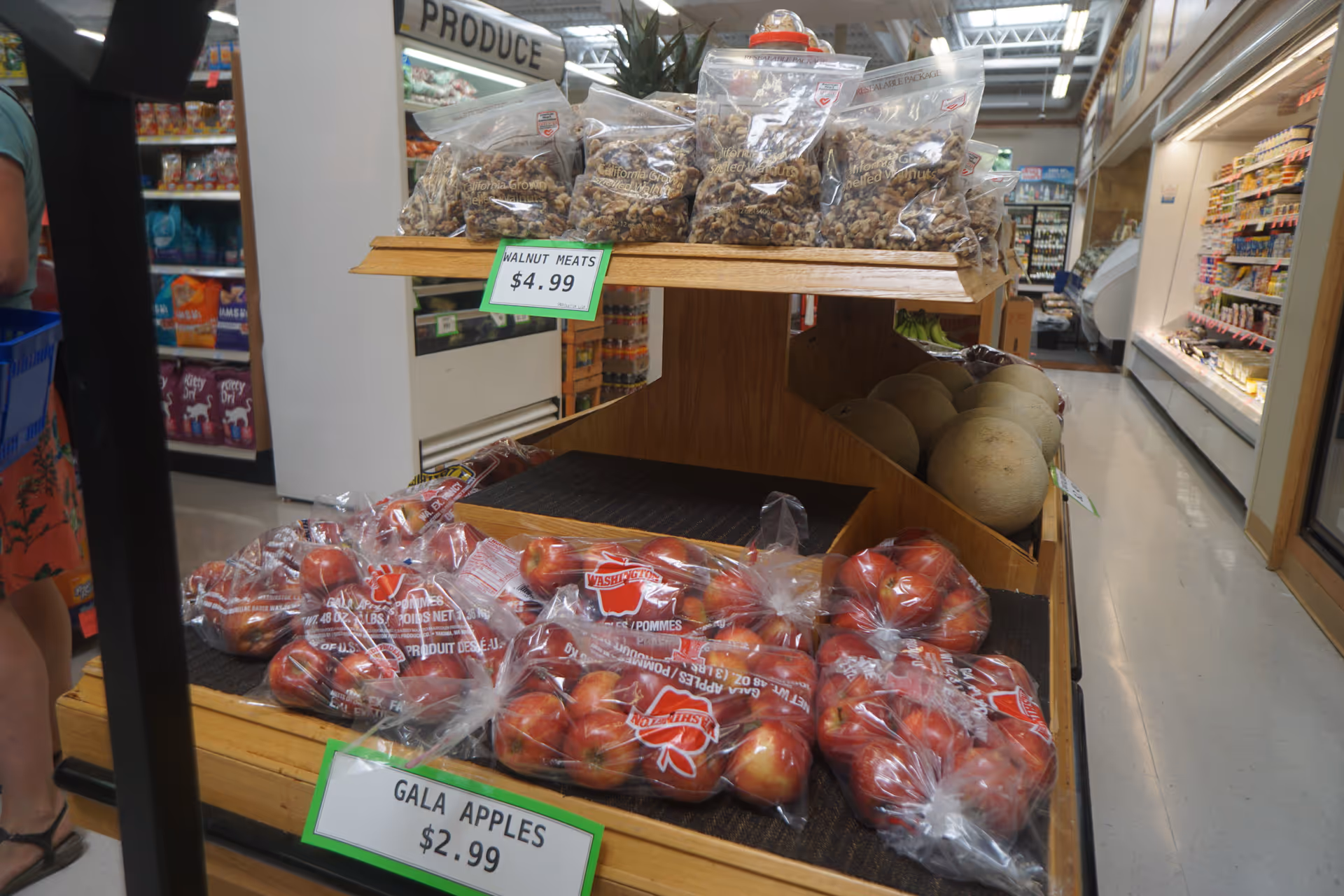 Produce display with bags of Gala apples and walnuts in a grocery store.