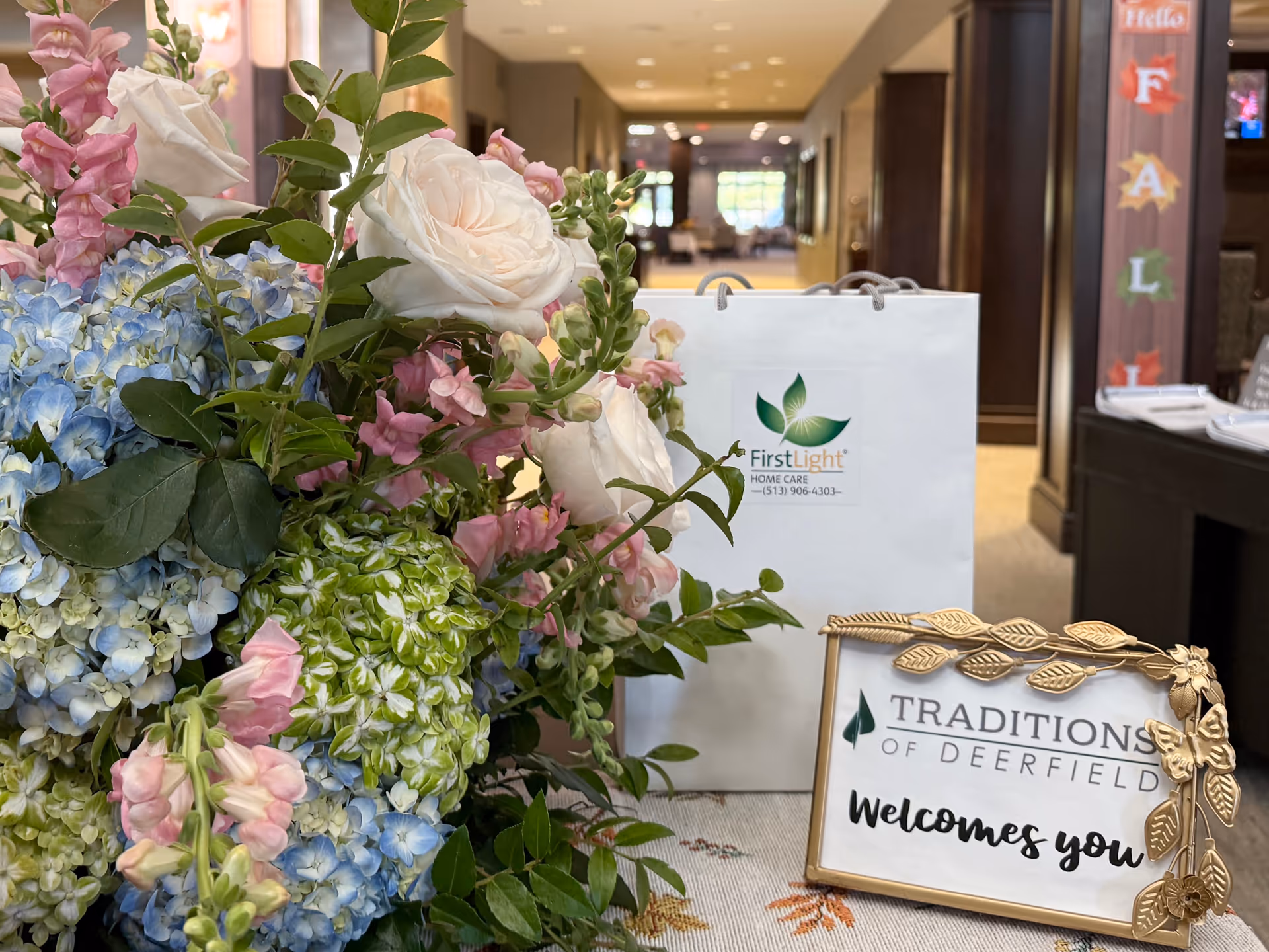 Colorful flower arrangement beside a FirstLight Home Care welcome sign in a facility lobby.