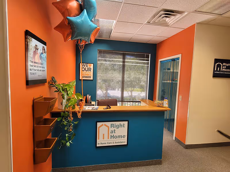 Reception desk inside a Right at Home facility with teal and orange walls and balloons.