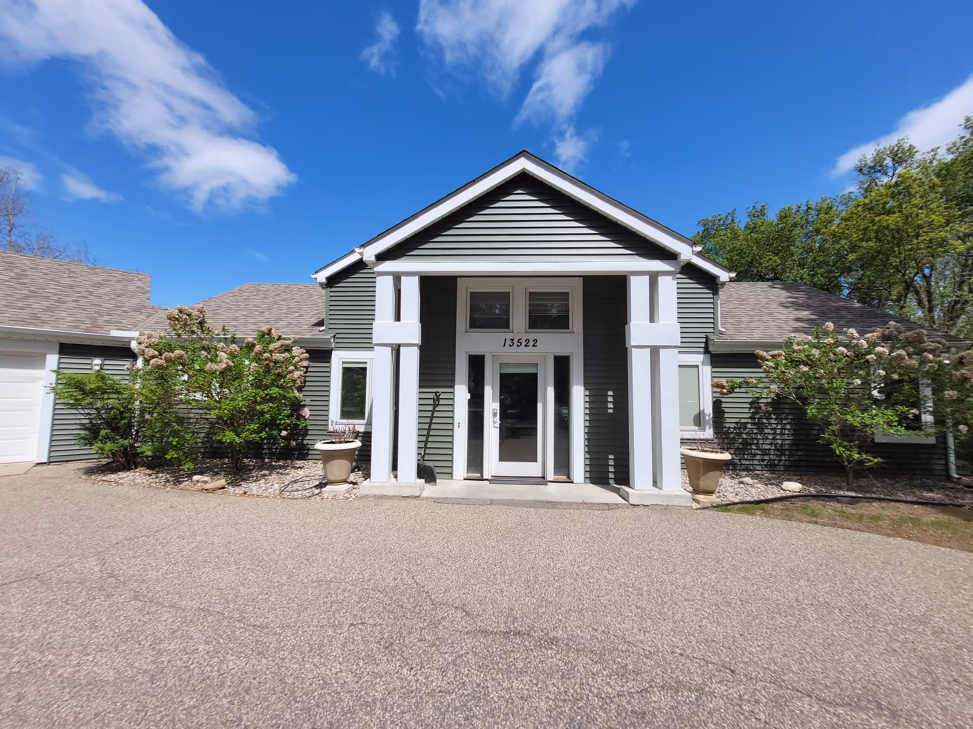 Front entrance of a gray, single-story senior living facility with columns.