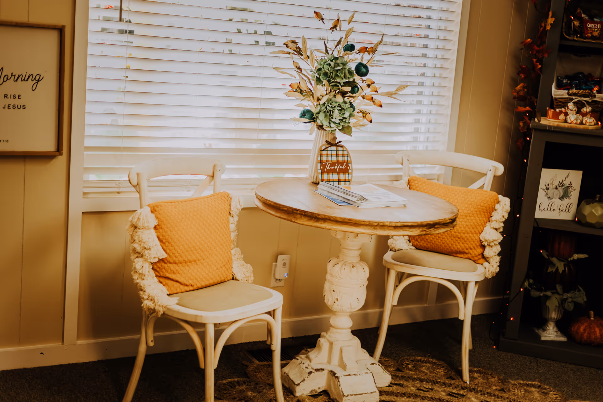 Cozy indoor seating area with two white chairs, orange cushions, and a round table