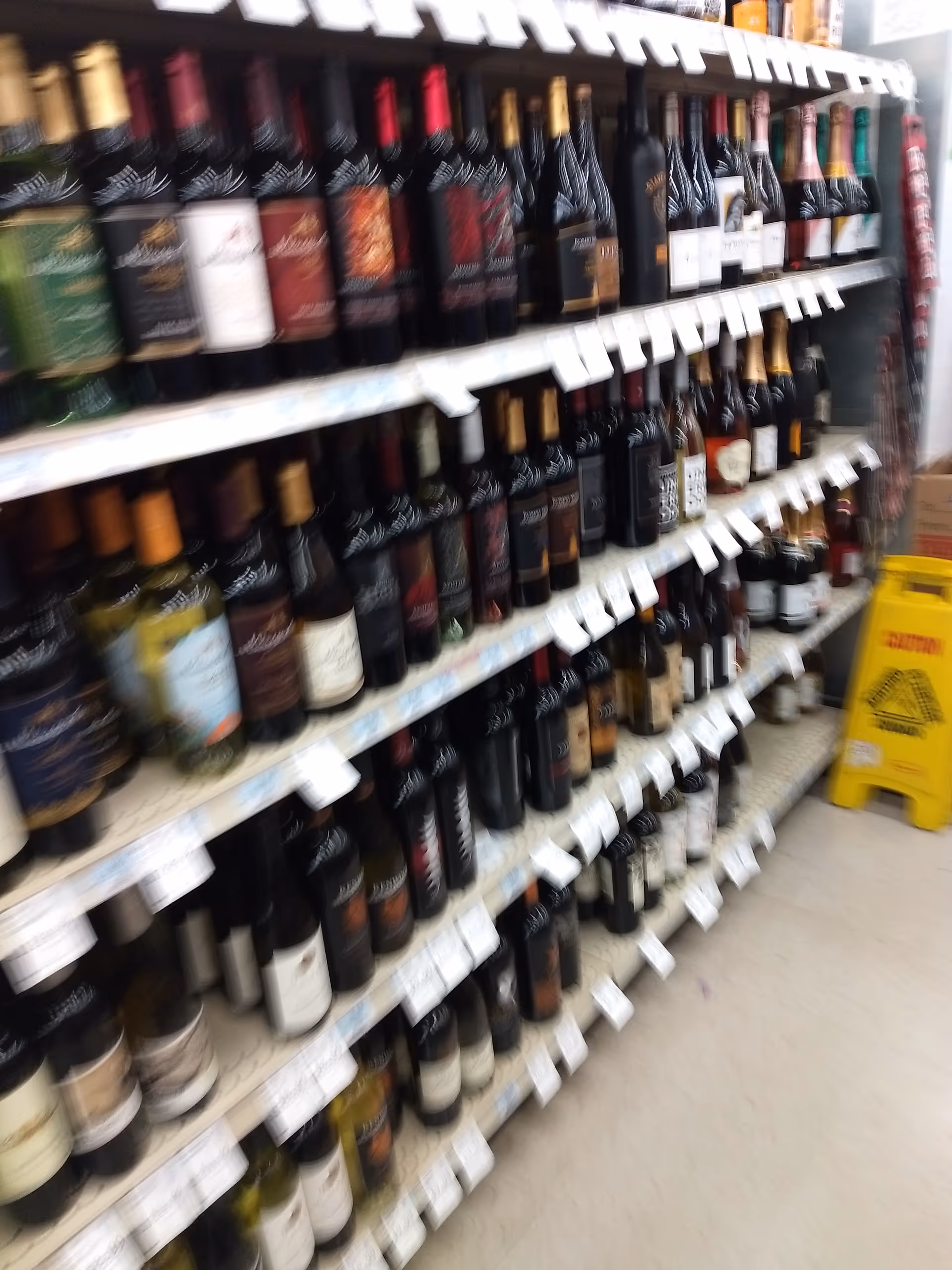 Rows of wine bottles line shelves in a liquor store aisle.