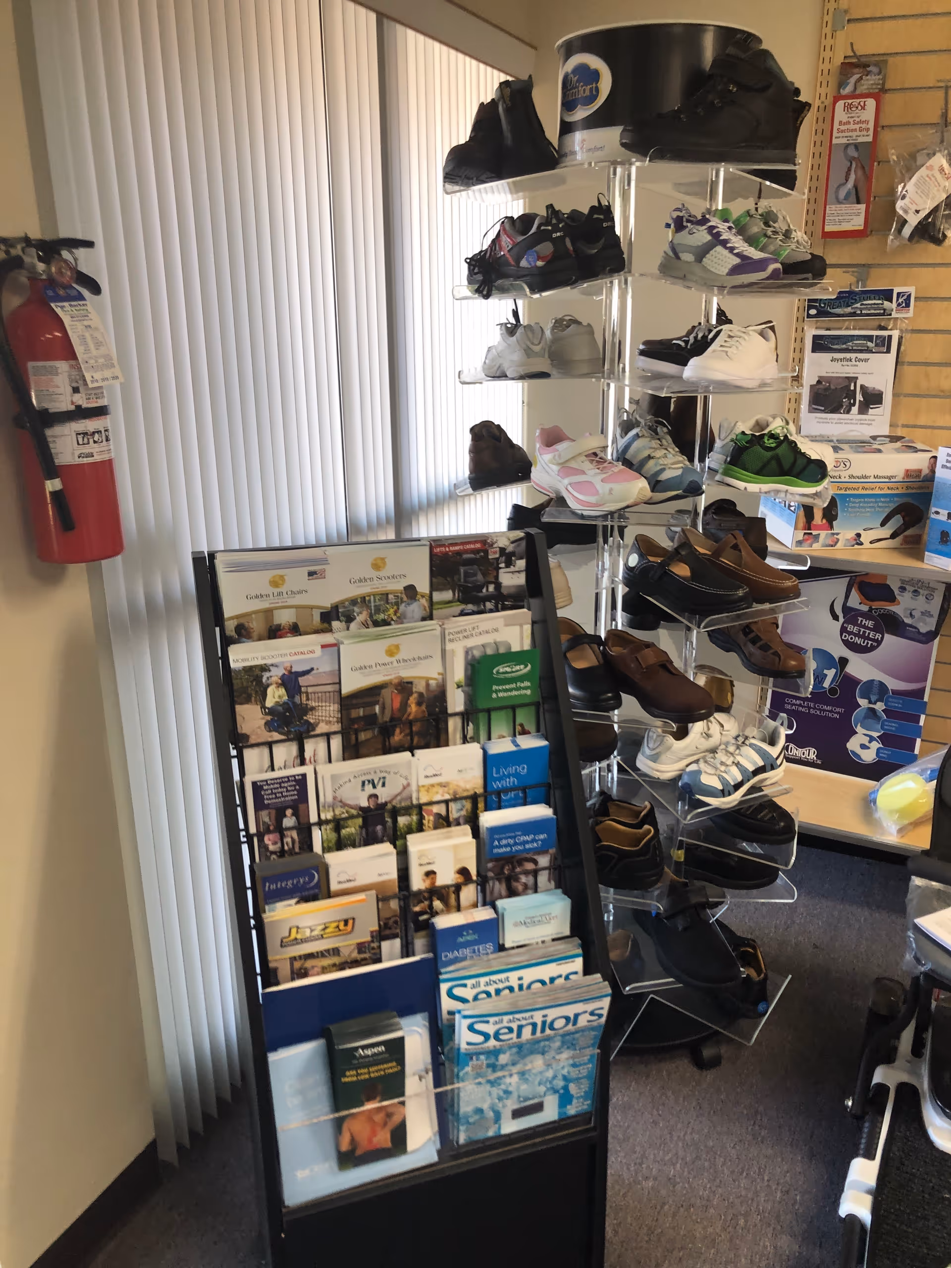 Shoe display rack with sneakers beside a brochure stand; fire extinguisher visible in facility store.