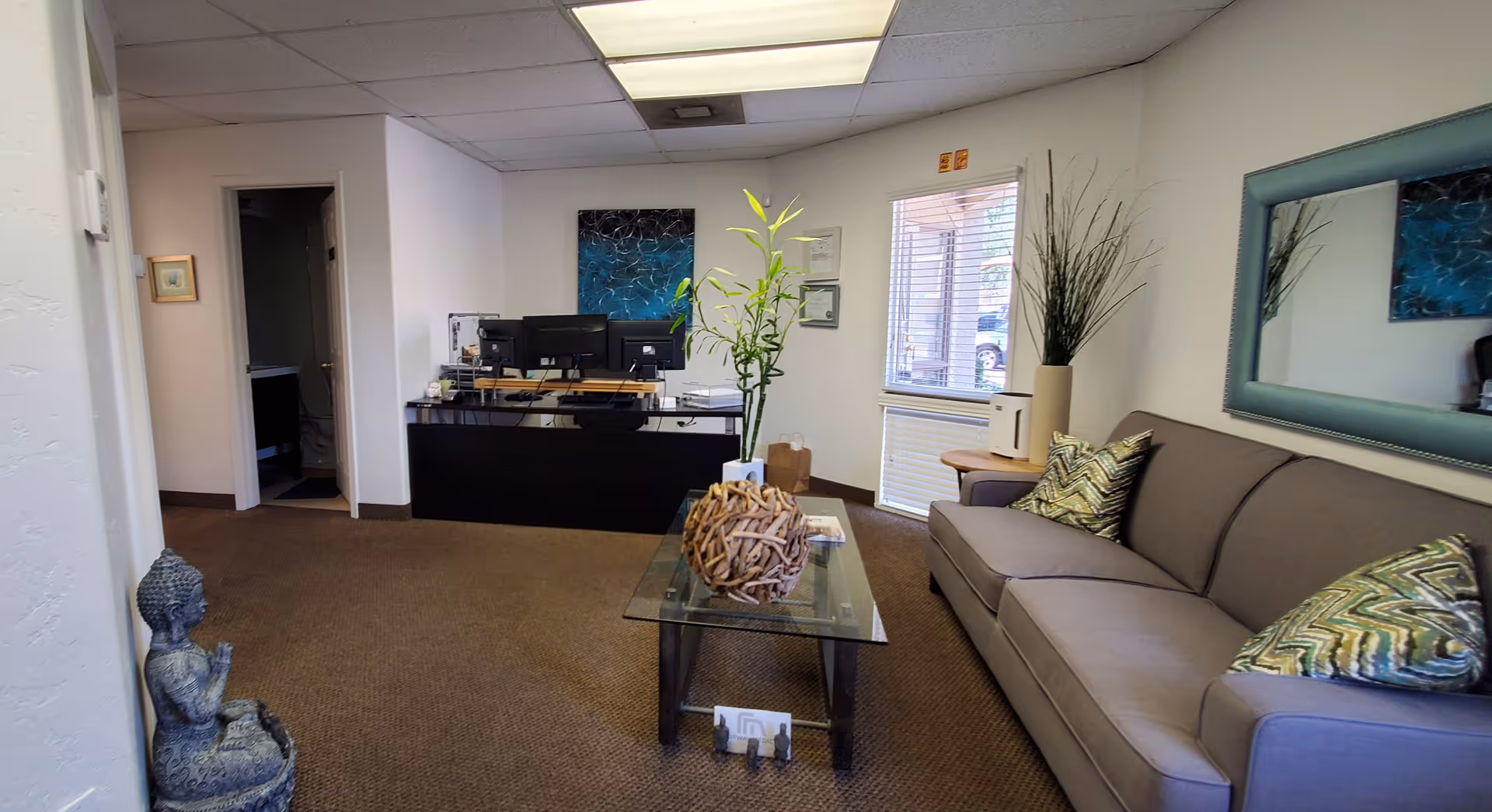 Reception area at Fairway Medical, featuring a desk, sofa, plants, and wall art.