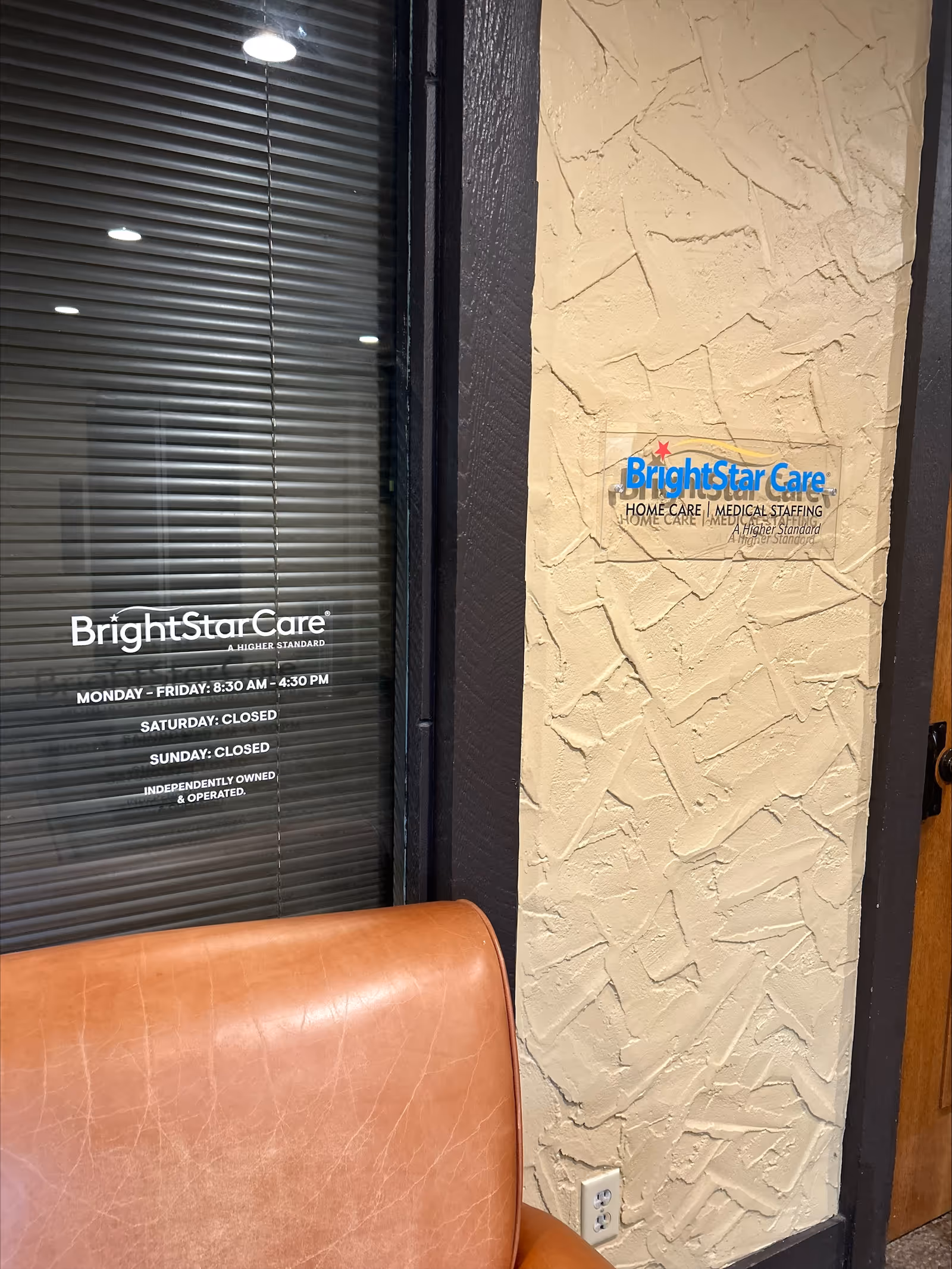 Interior entrance with BrightStar Care sign on textured wall beside glass door and blinds.