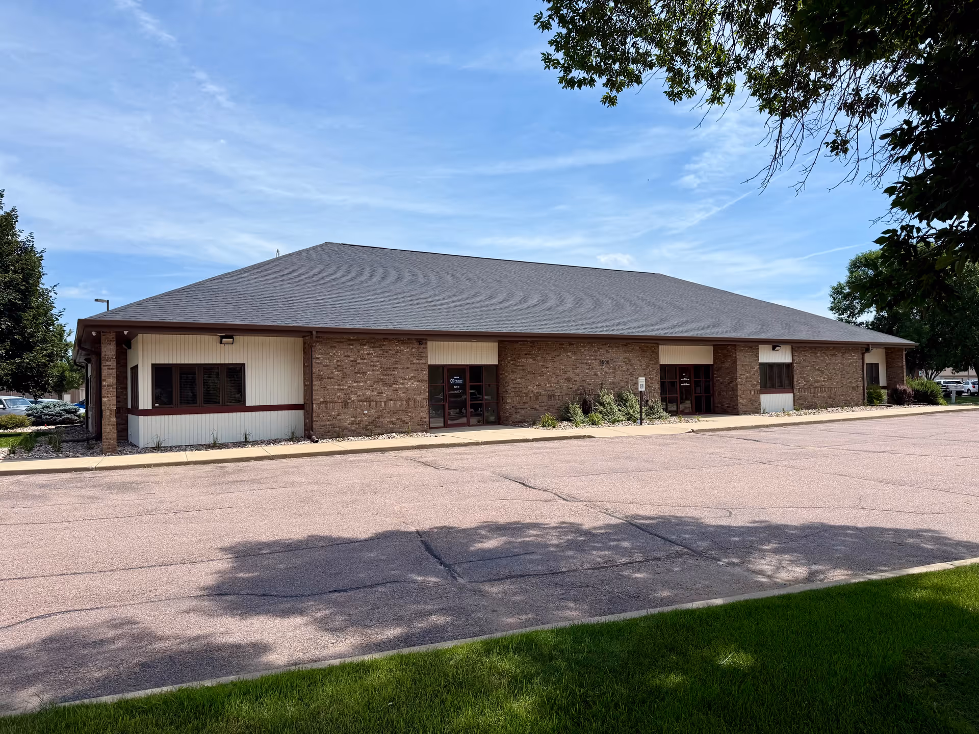 Single-story brick senior care building with parking lot and blue sky.