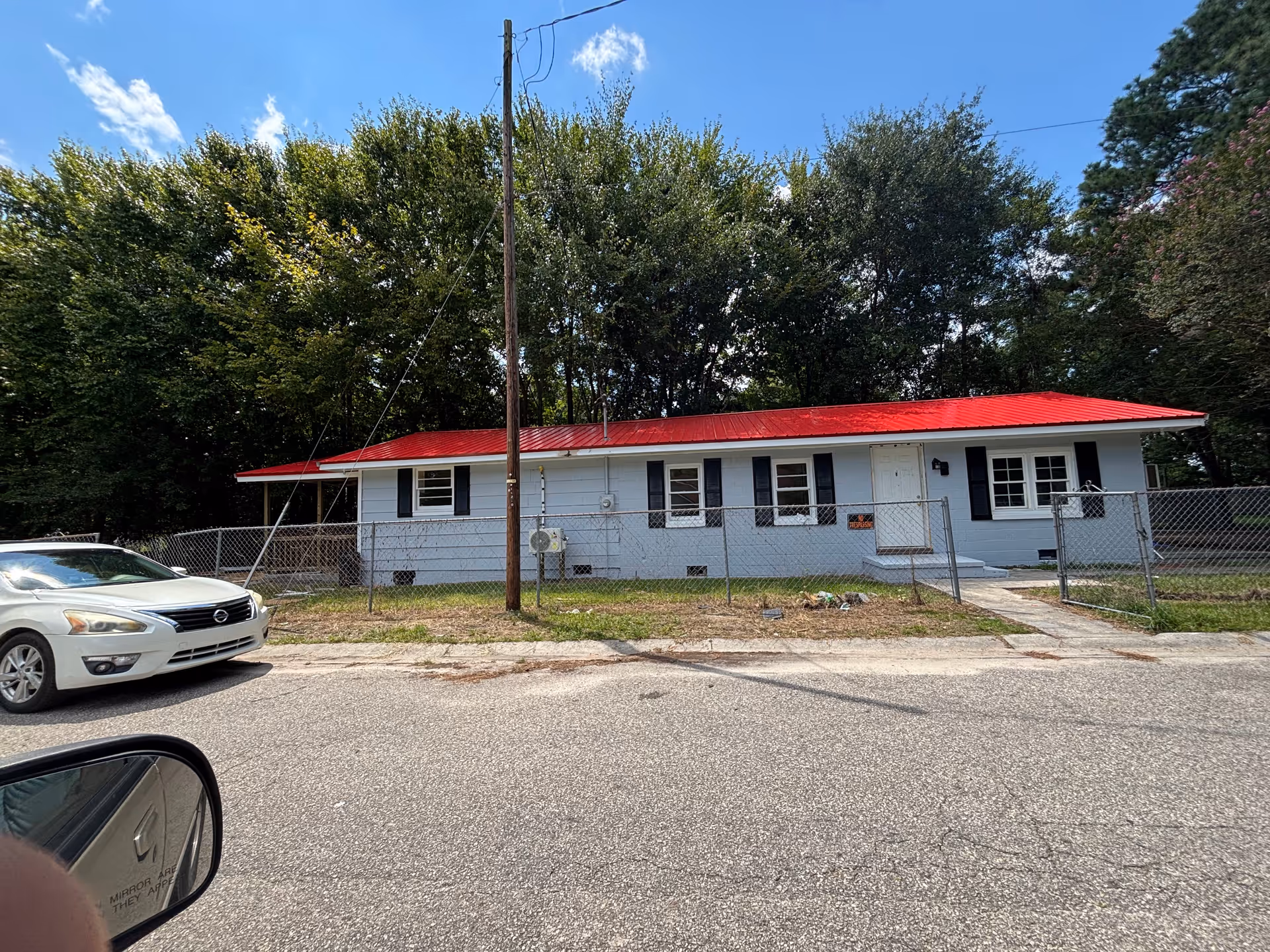 A single story building with a red roof and chain link fence on a residential street.