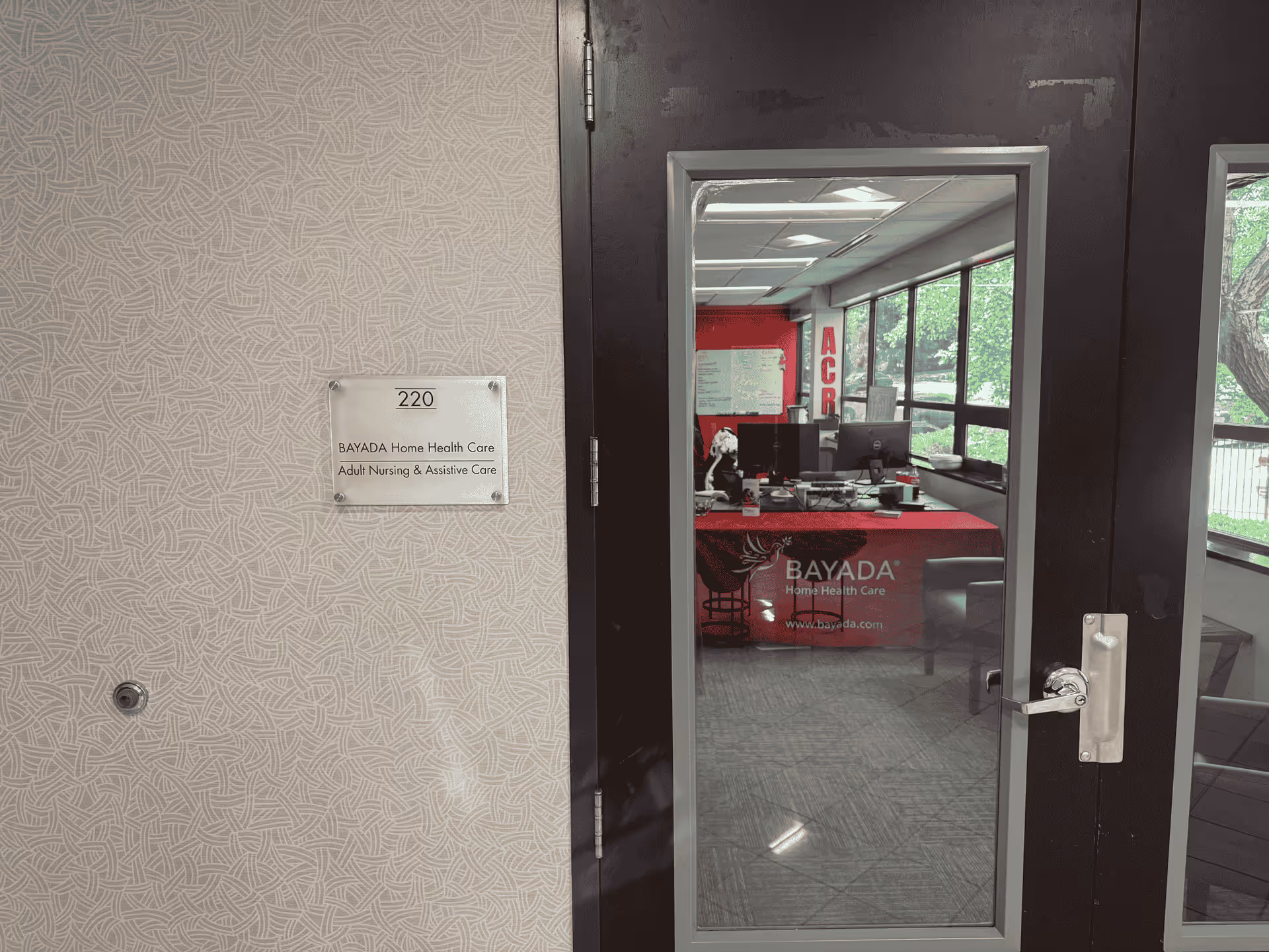 Doorway opens to an interior reception area featuring BAYADA branding and a desk.