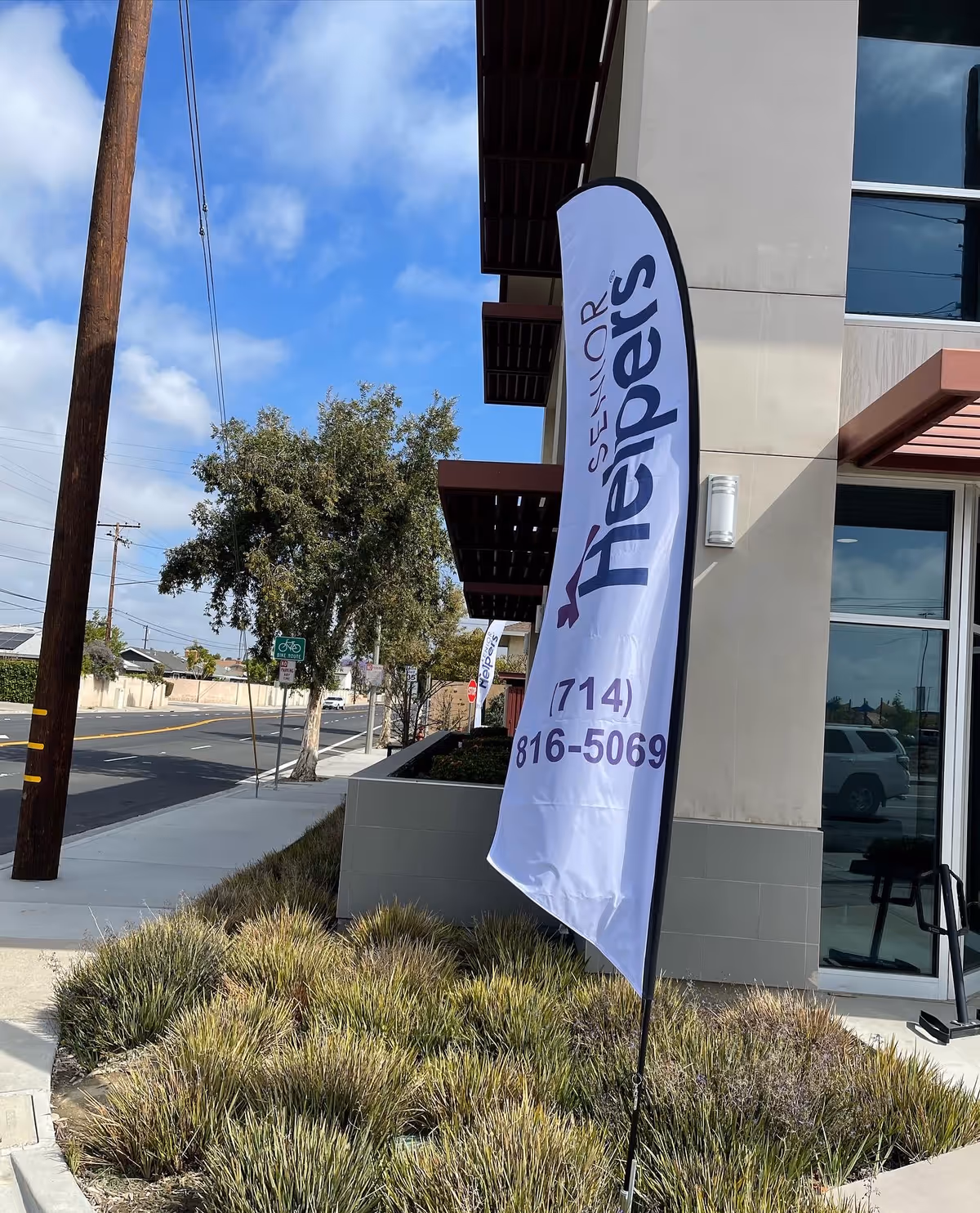 Exterior view of a Senior Helpers facility with a vertical banner flag.