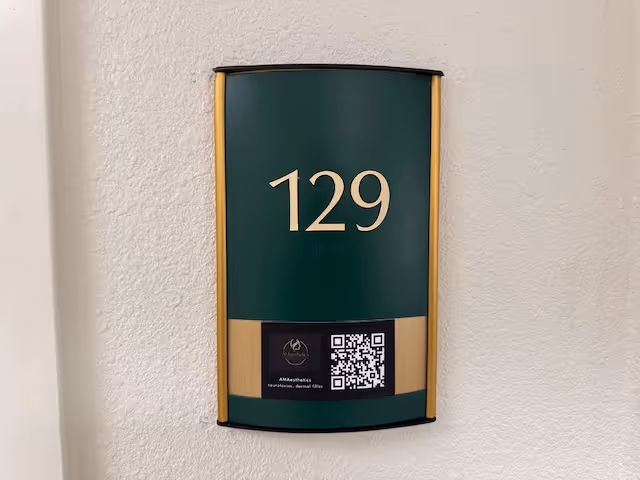 Close-up wall plaque showing unit number 129 and a QR code.