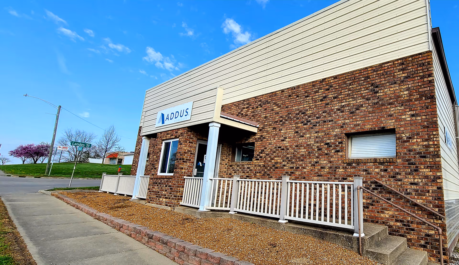 Addus HomeCare front entrance with brick exterior and white railing.