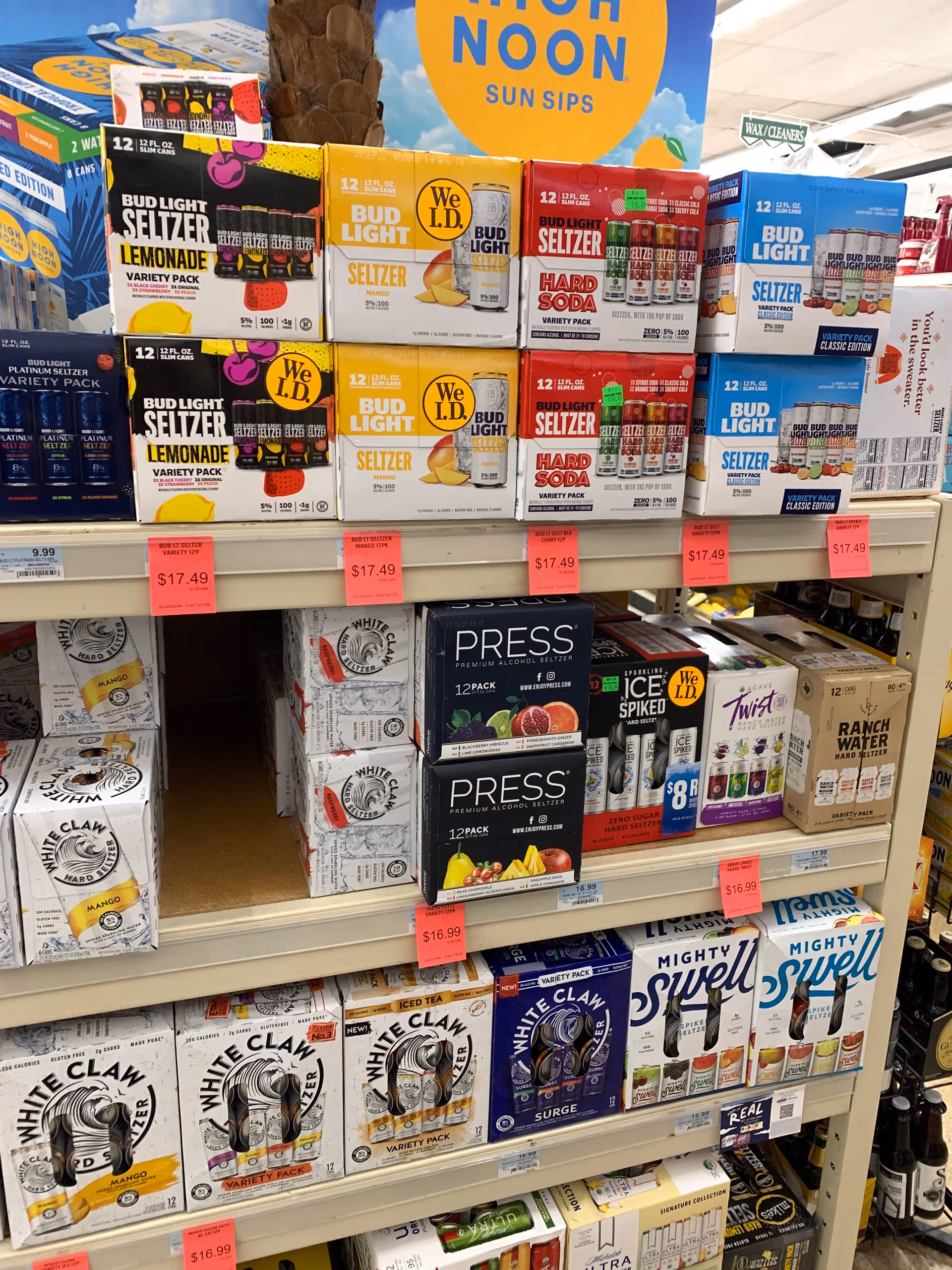 Rows of alcohol boxes, including Bud Light Seltzer and White Claw, on store shelves.