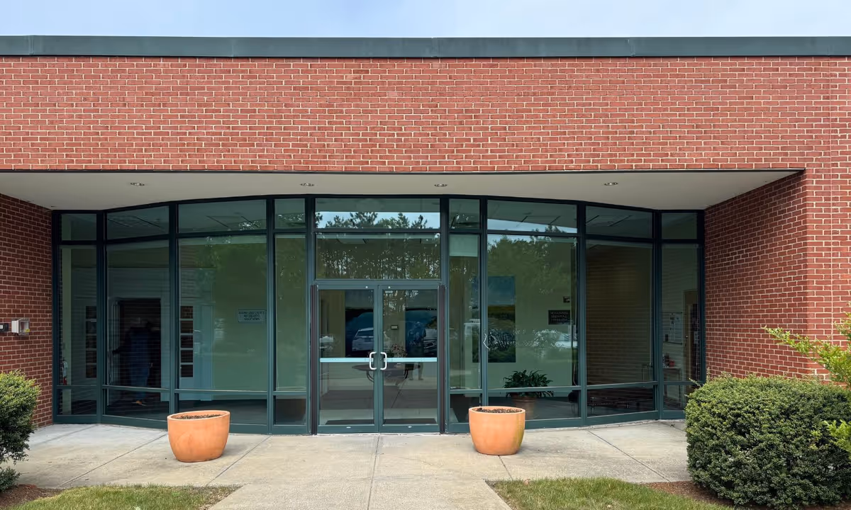 Brick building exterior with glass doors and minimal landscaping, showing BAYADA Assistive Care facility entrance.
