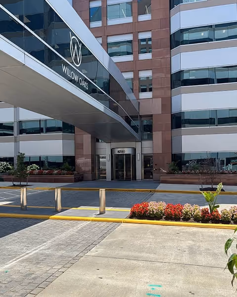 Modern multi-story senior living building with glass windows and a covered entrance labeled Willow Oaks