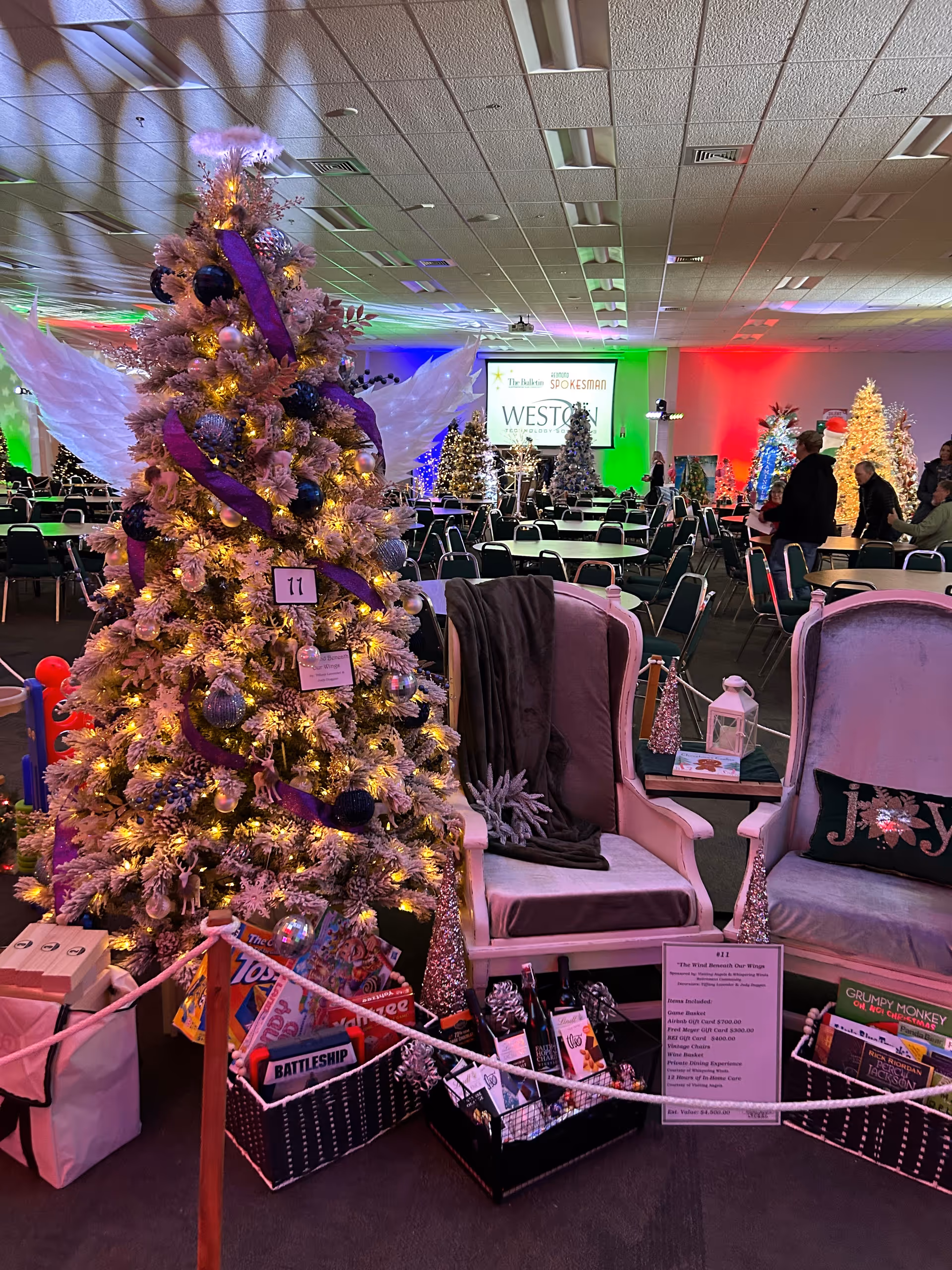 Festive indoor senior home hall with decorated trees, chairs, and a stage.