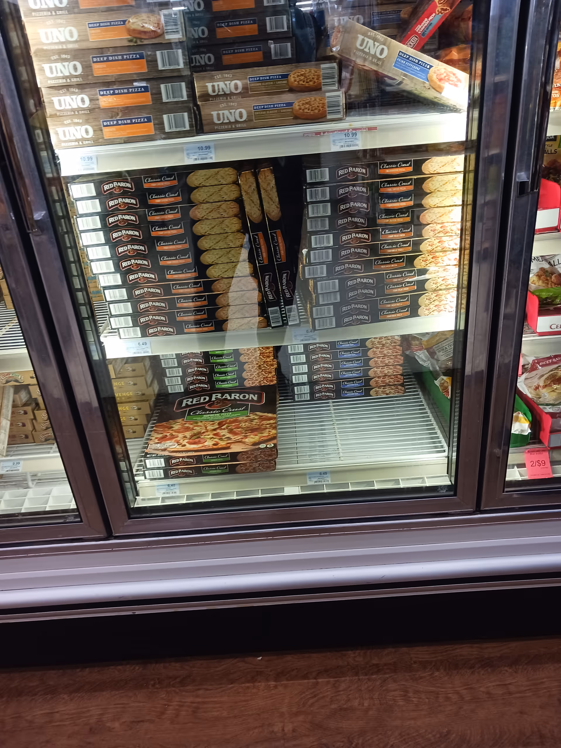 A store's glass-door freezer stocked with UNO and Red Baron frozen pizzas