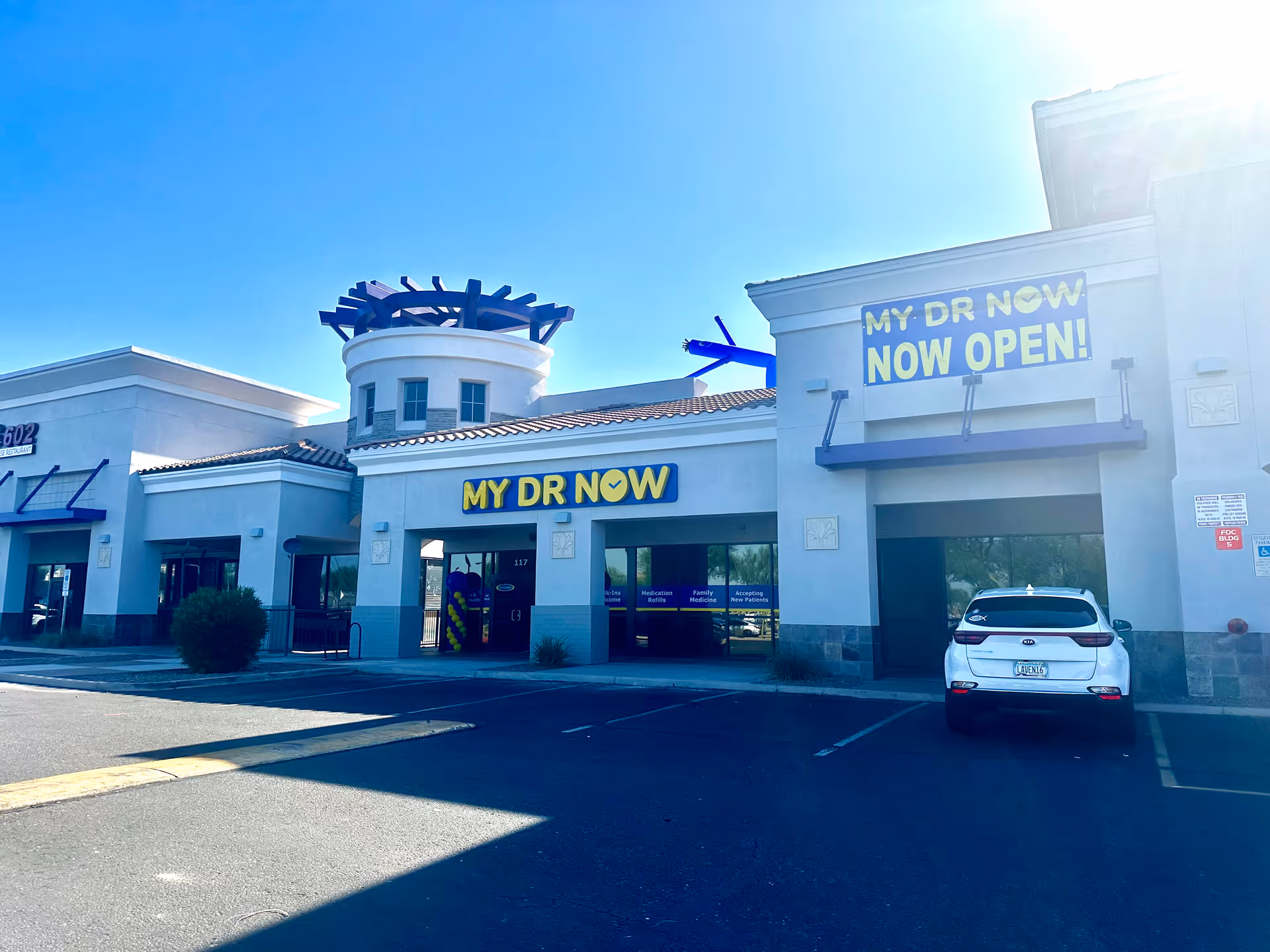 Front exterior of a My Dr Now facility with blue signage and a parked white SUV.