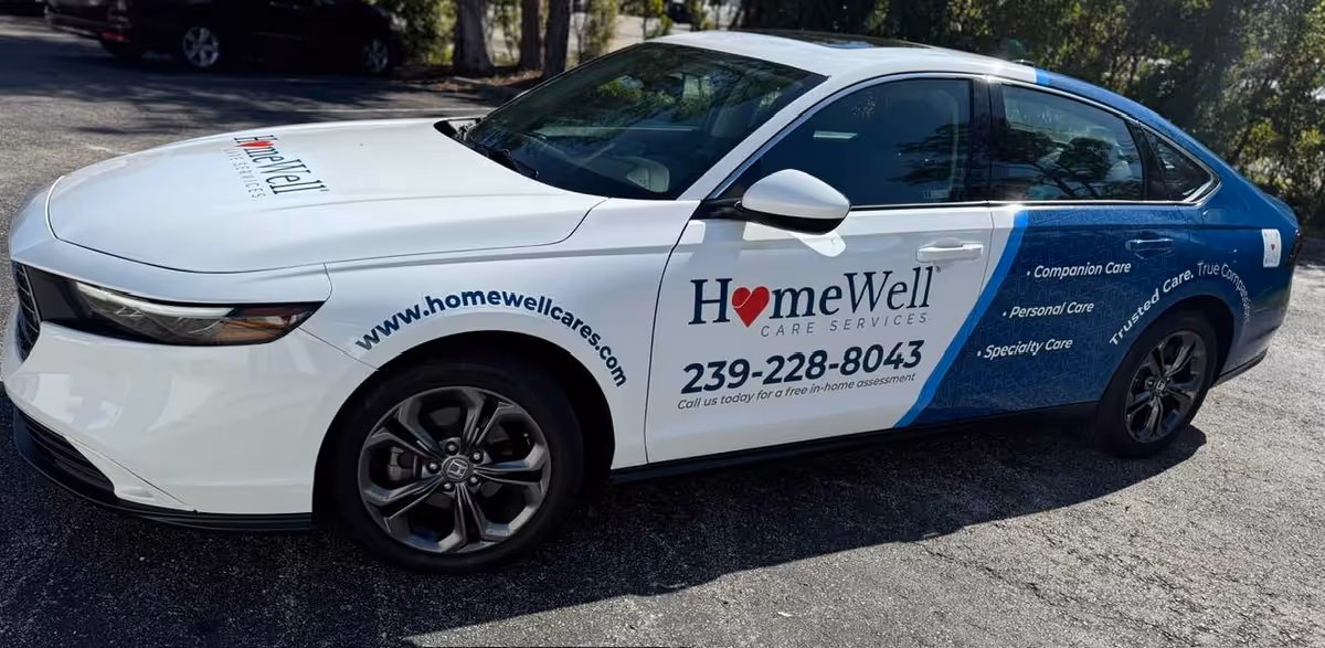 White and blue HomeWell Care Services promotional car parked outdoors.