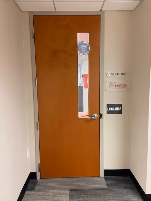 Wooden interior door in a hallway with entrance sign and BAYADA suite labels.