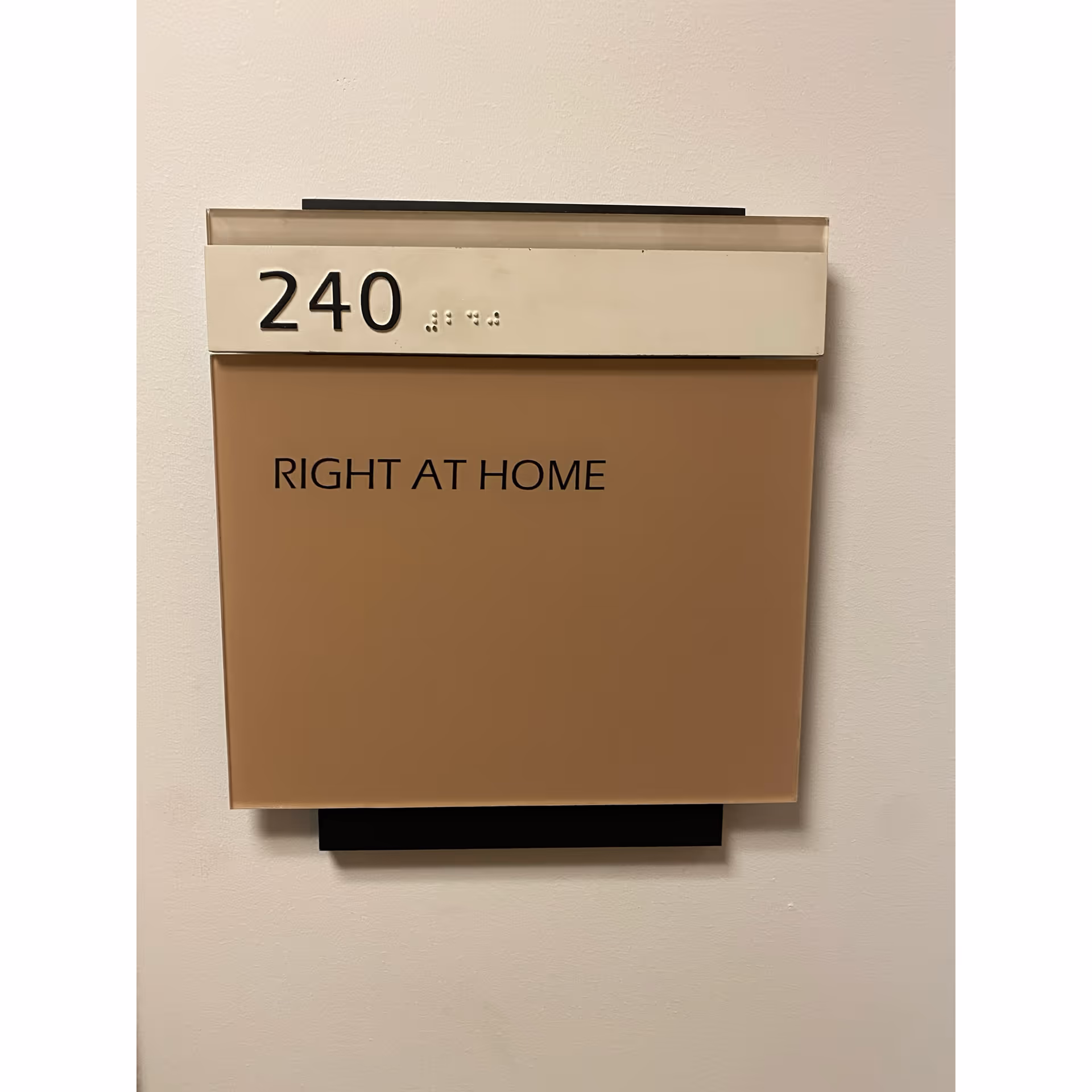 Beige wall panel with Room 240 and Right at Home branding.