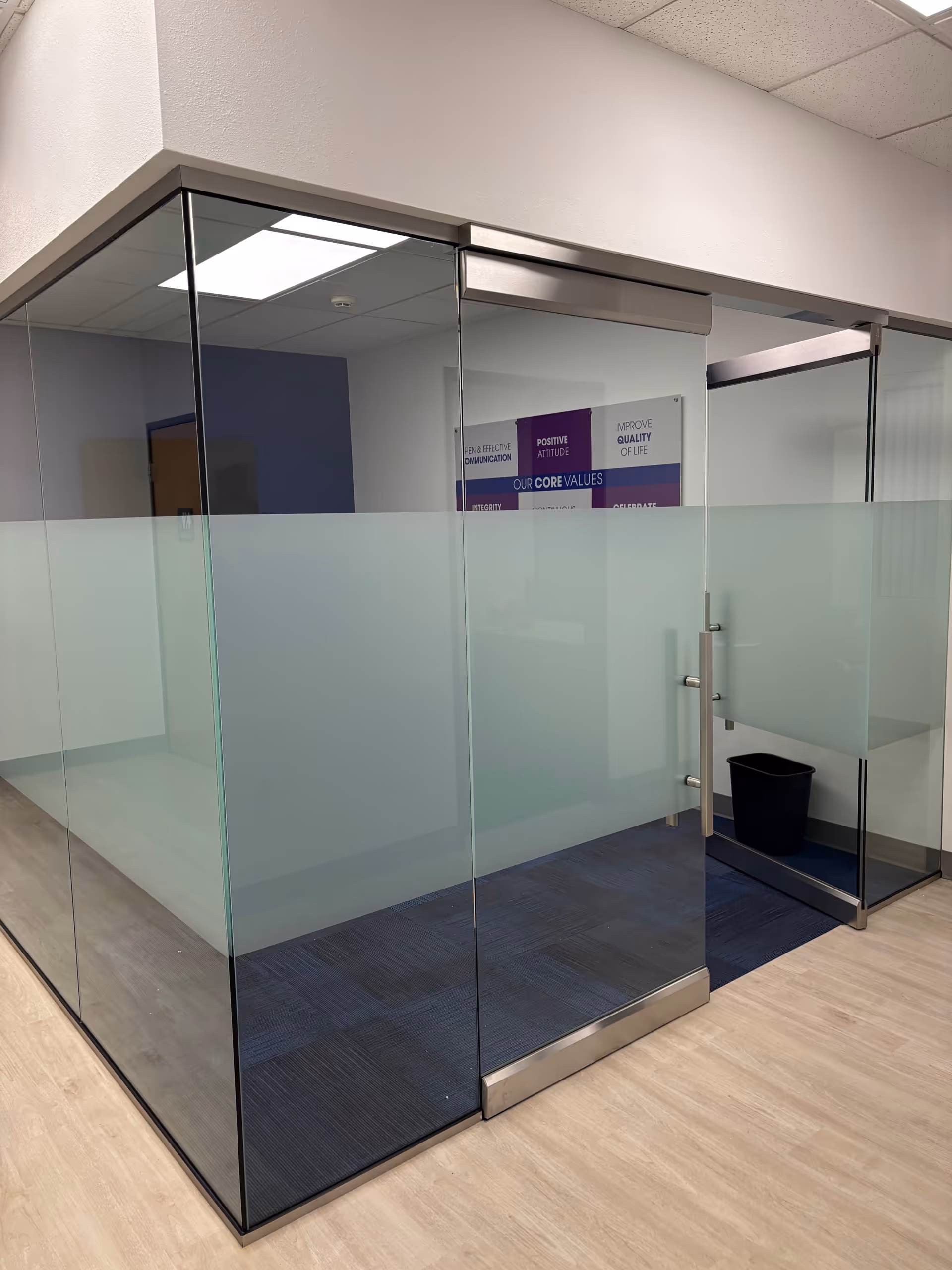 Glass-walled cubicles line a frosted hallway inside a Senior Helpers facility.