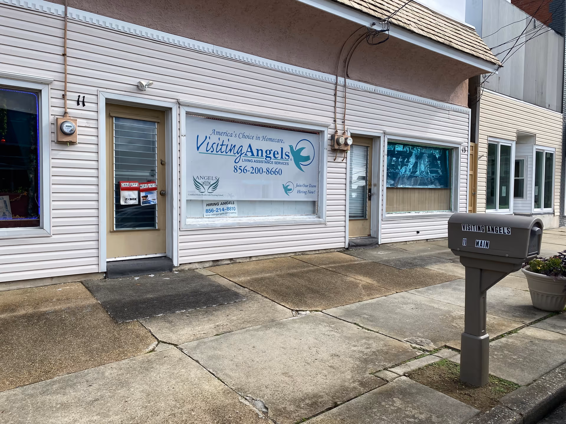 Front view of a beige storefront with Visiting Angels signage and a mailbox.