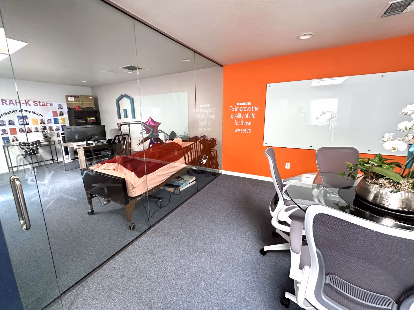 Hospital bed in glass-walled patient room at Right at Home senior care facility.